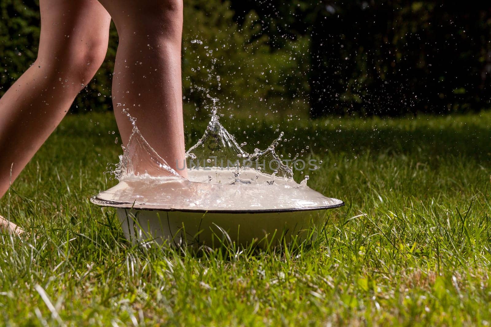 Little boy and splash of water in the summer garden