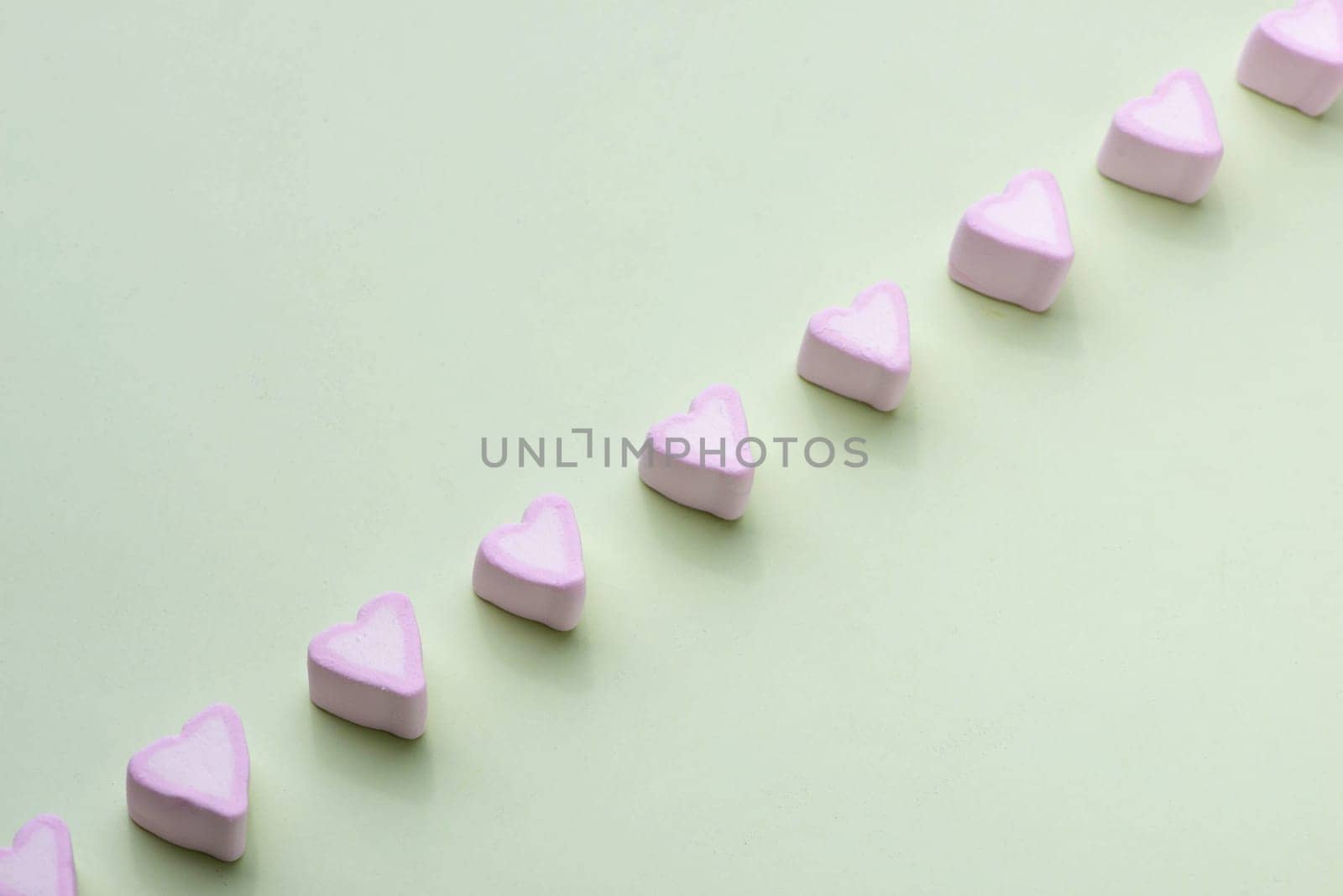 Valentines Day candy hearts marshmallows over green background