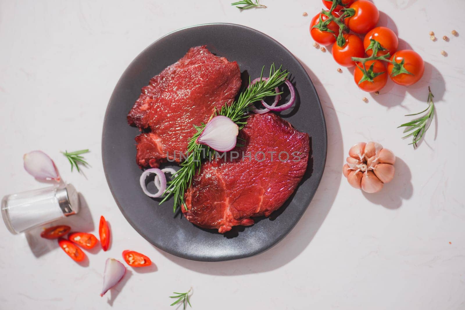 Raw beef on a cutting board  with spices and ingredients for cooking.