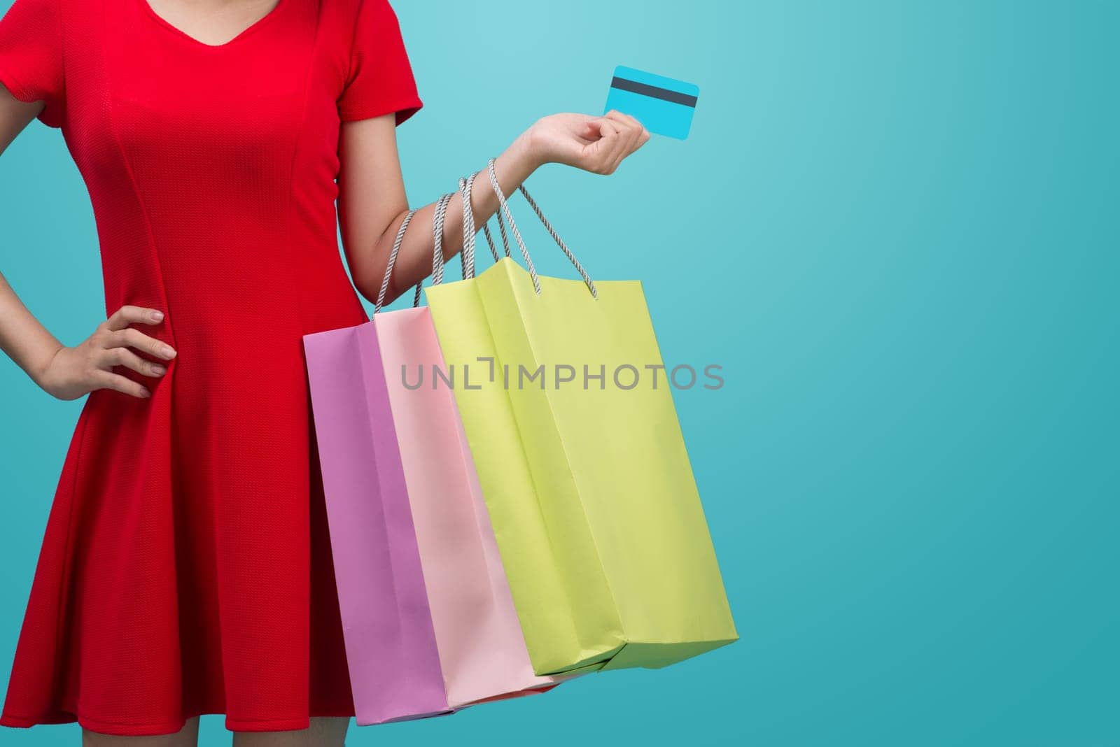 Asian girl showing credit card in hand, over blue background