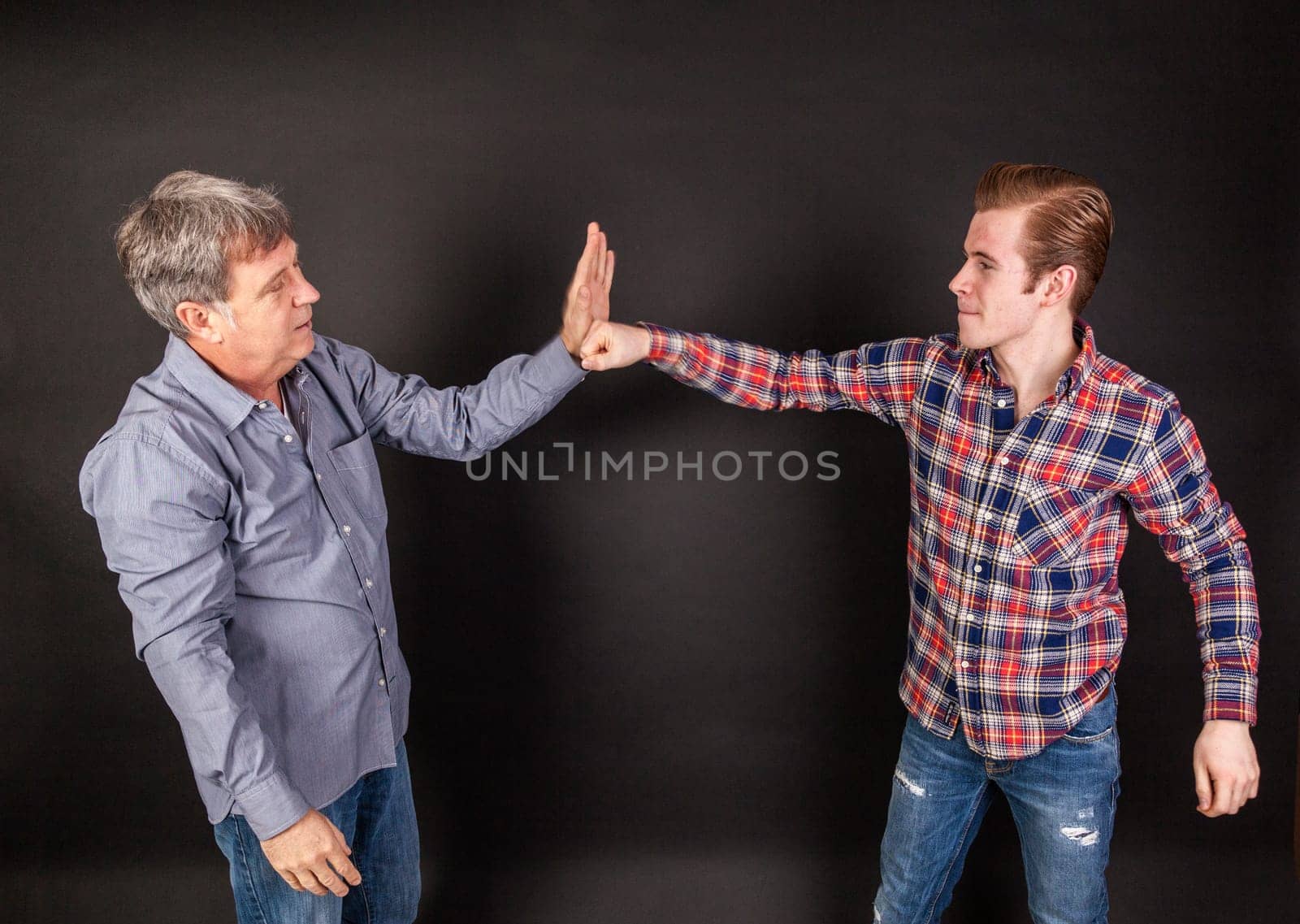 father and son lean on back to back isolated on black
