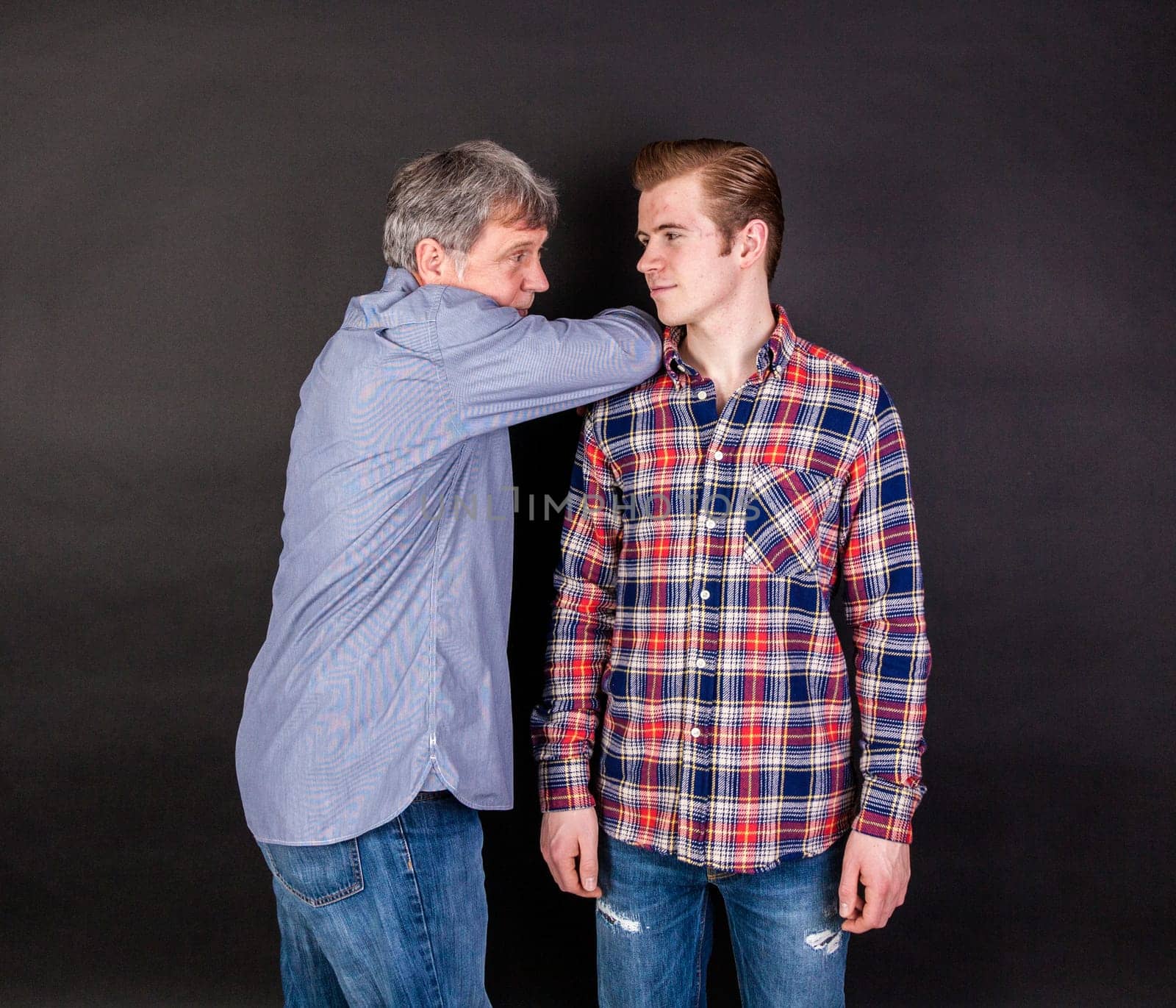 father and son lean on back to back isolated on black