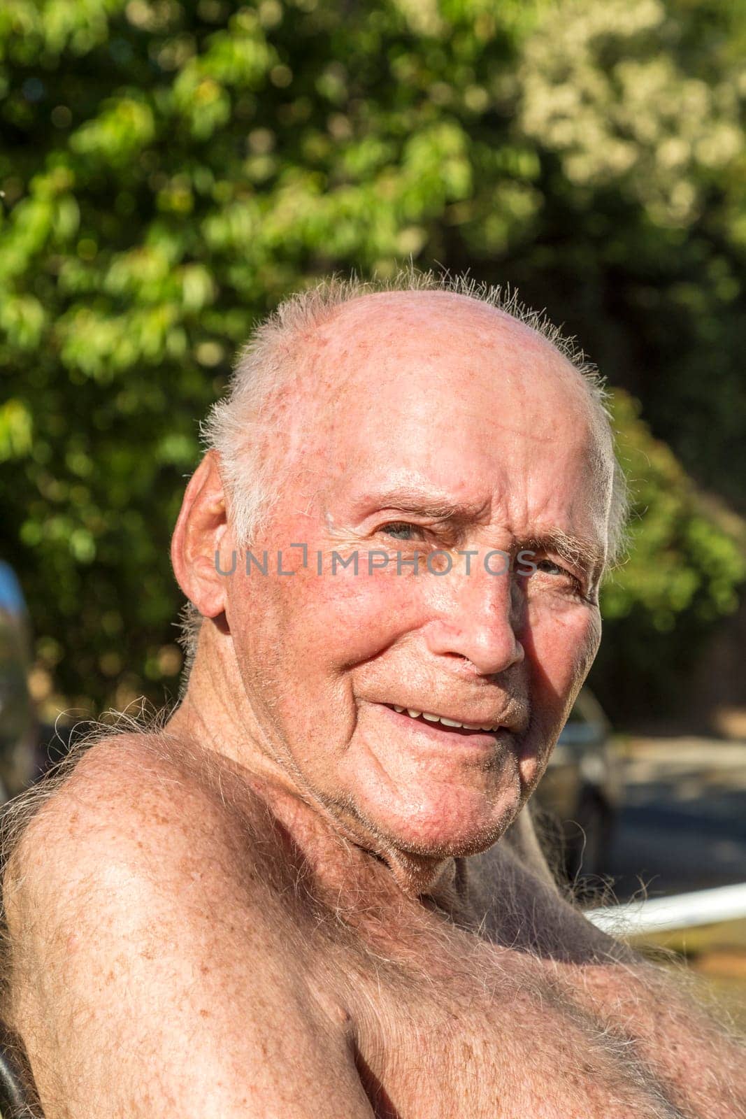 senior sits in the chair in the garden and enjoys the sun