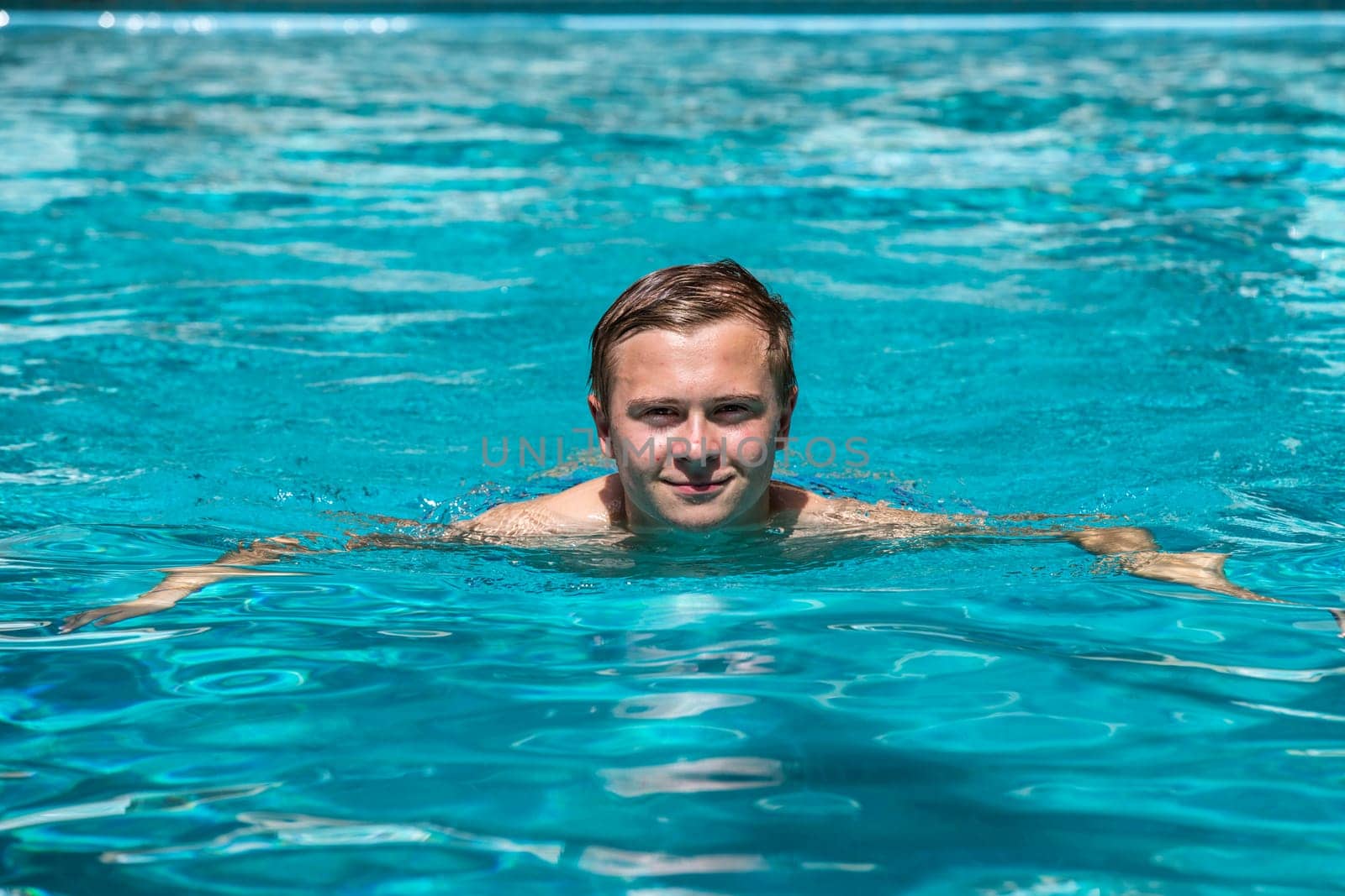 boy enjoys swimming in the outdoor swimming pool
