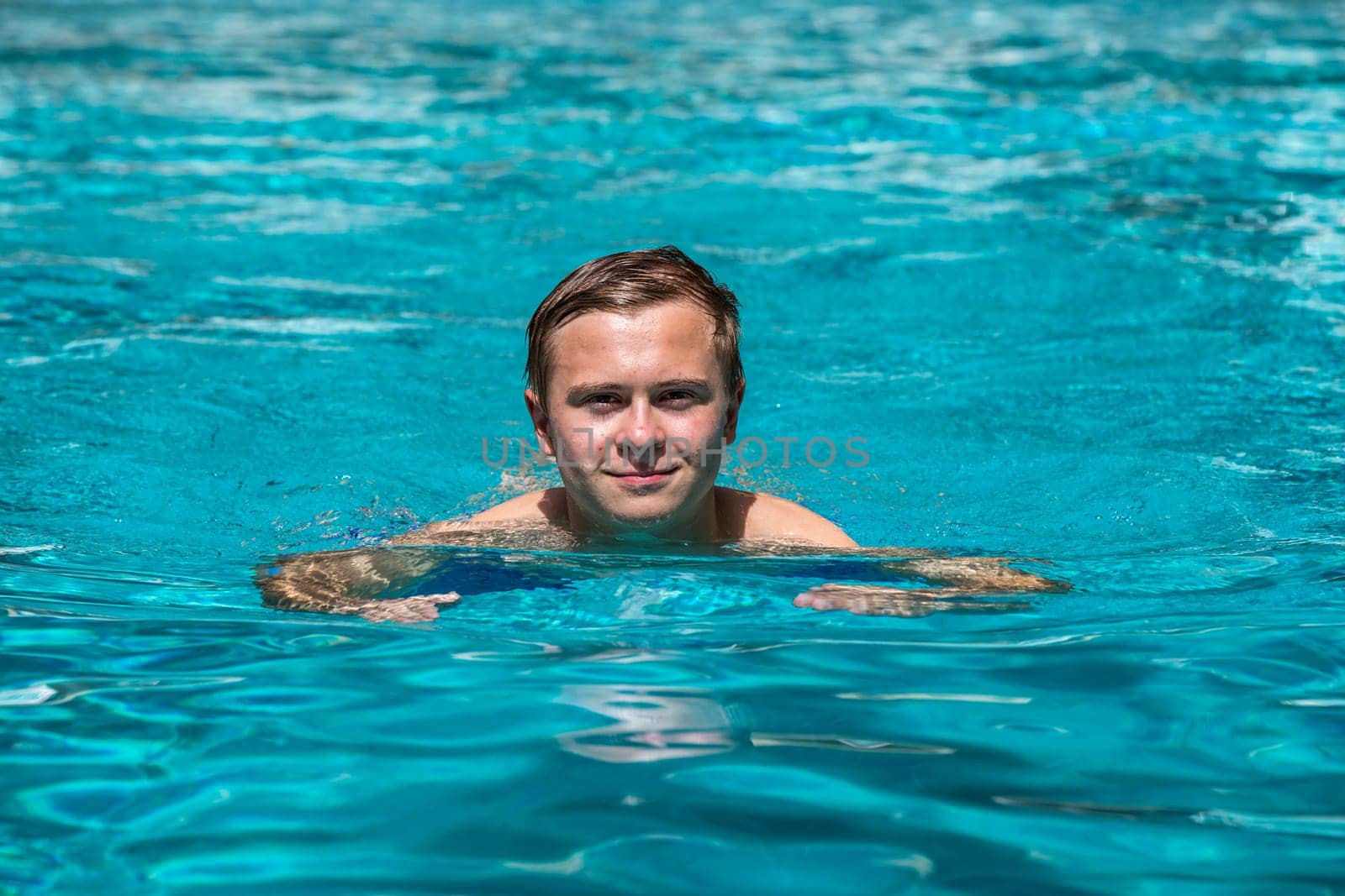 boy enjoys swimming in the outdoor swimming pool