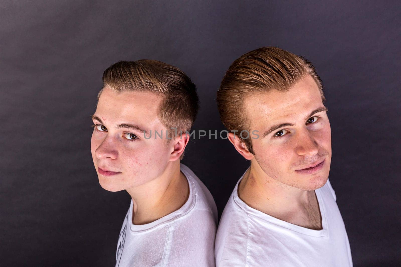 two teenage brothers standing back to back and have fun