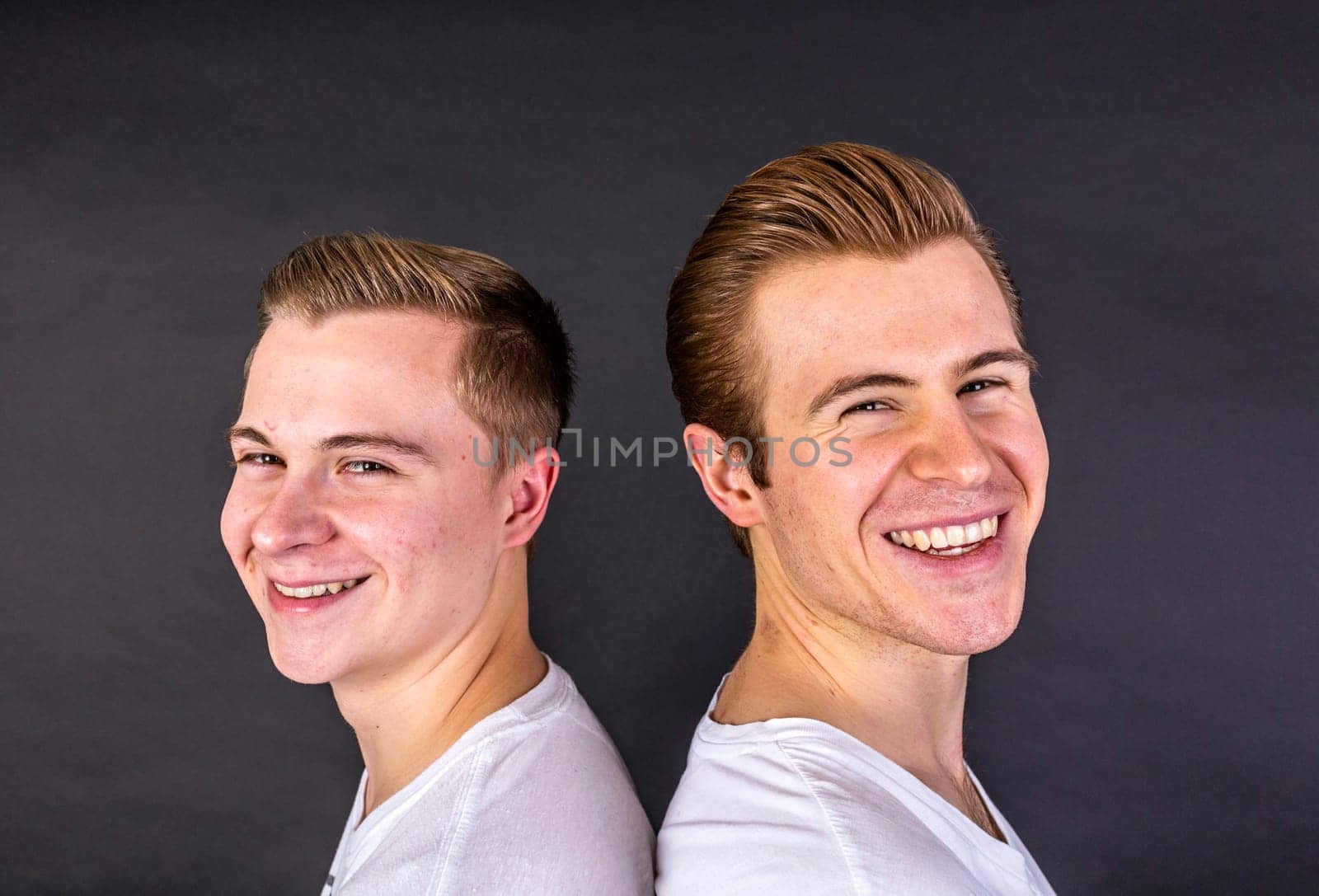 two teenage brothers standing back to back and have fun