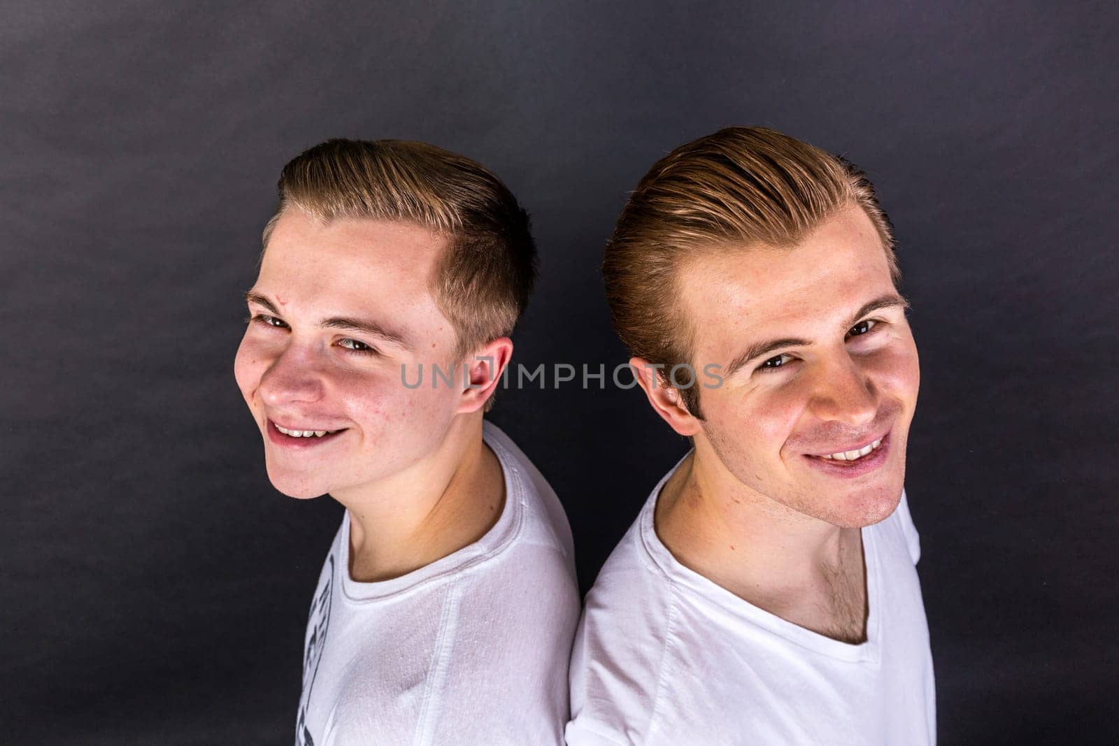two teenage brothers standing back to back and have fun