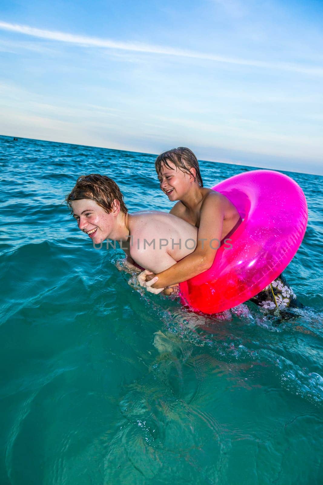 two brothers in a swim ring have fun in the ocean