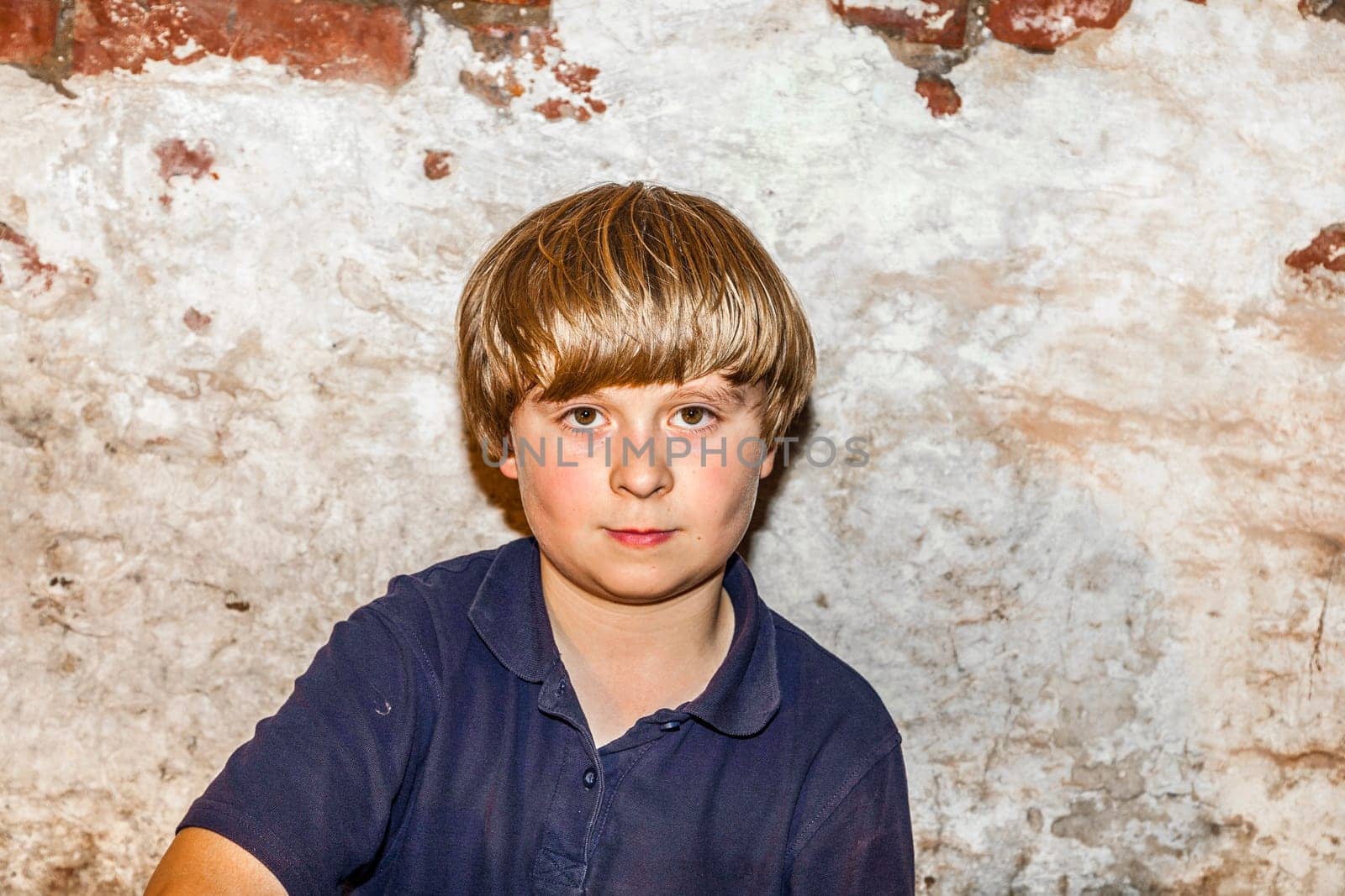 portrait of a cute young boy with old brick background
