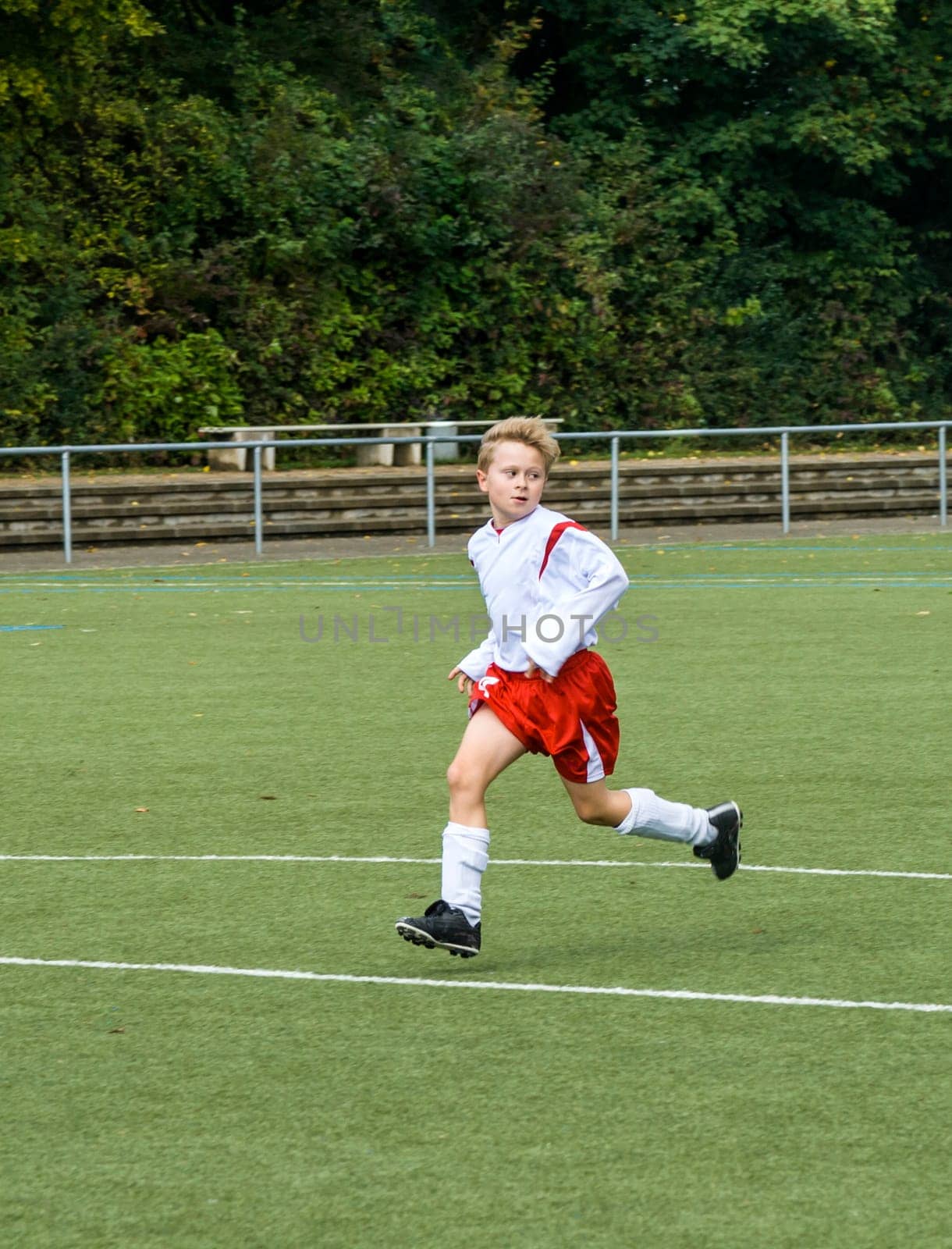 young soccer player runs over the green football ground