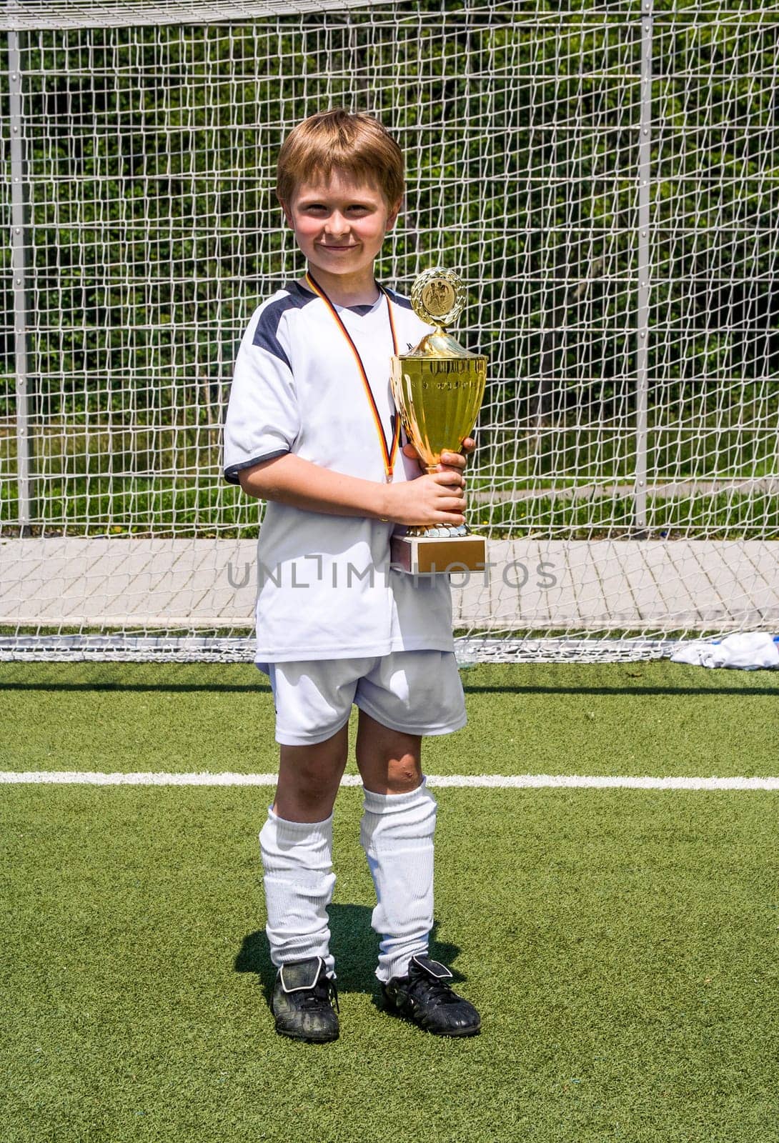 child keeps proudly the cup in its hand after the match