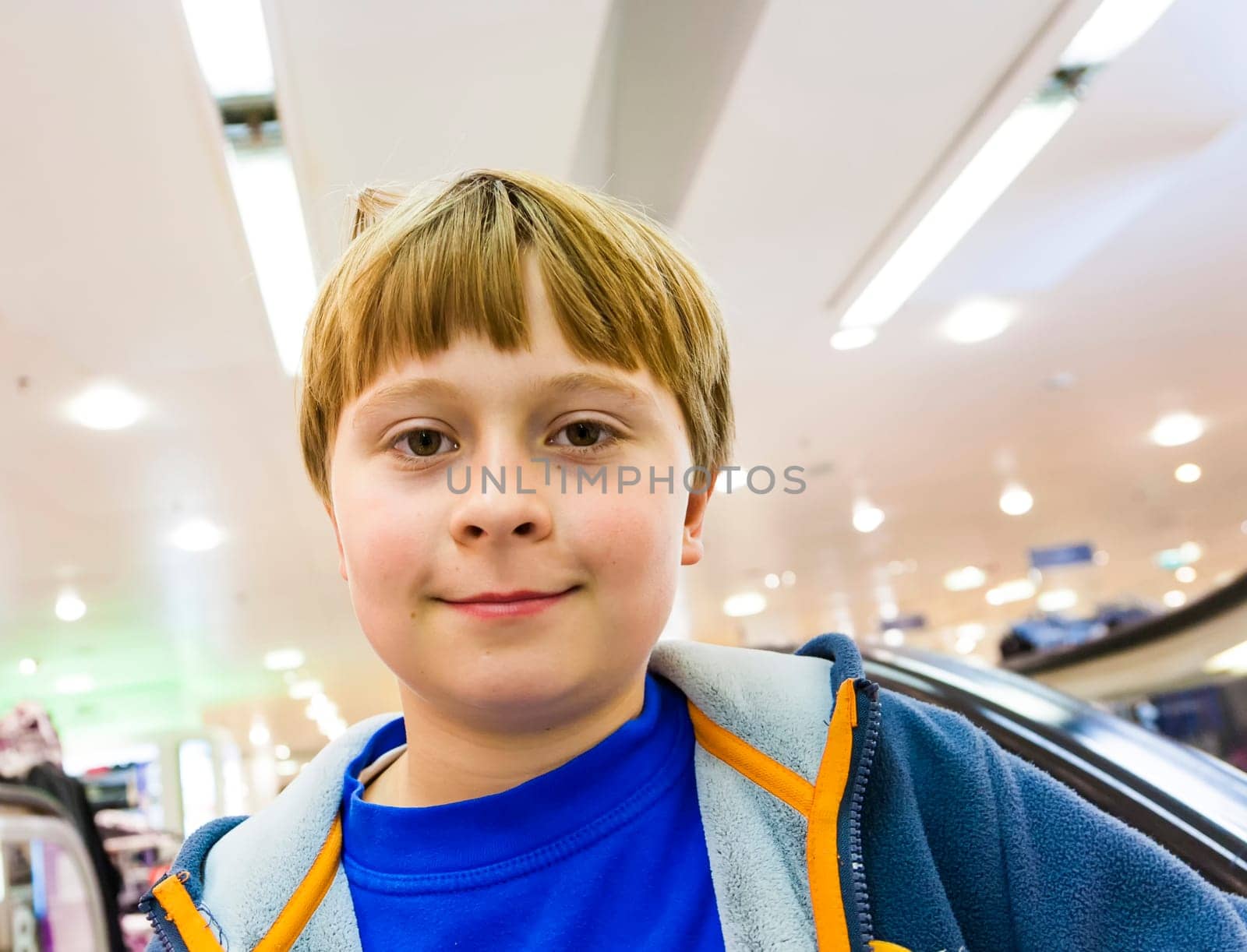 child on moving staircase looks self confident and smiles