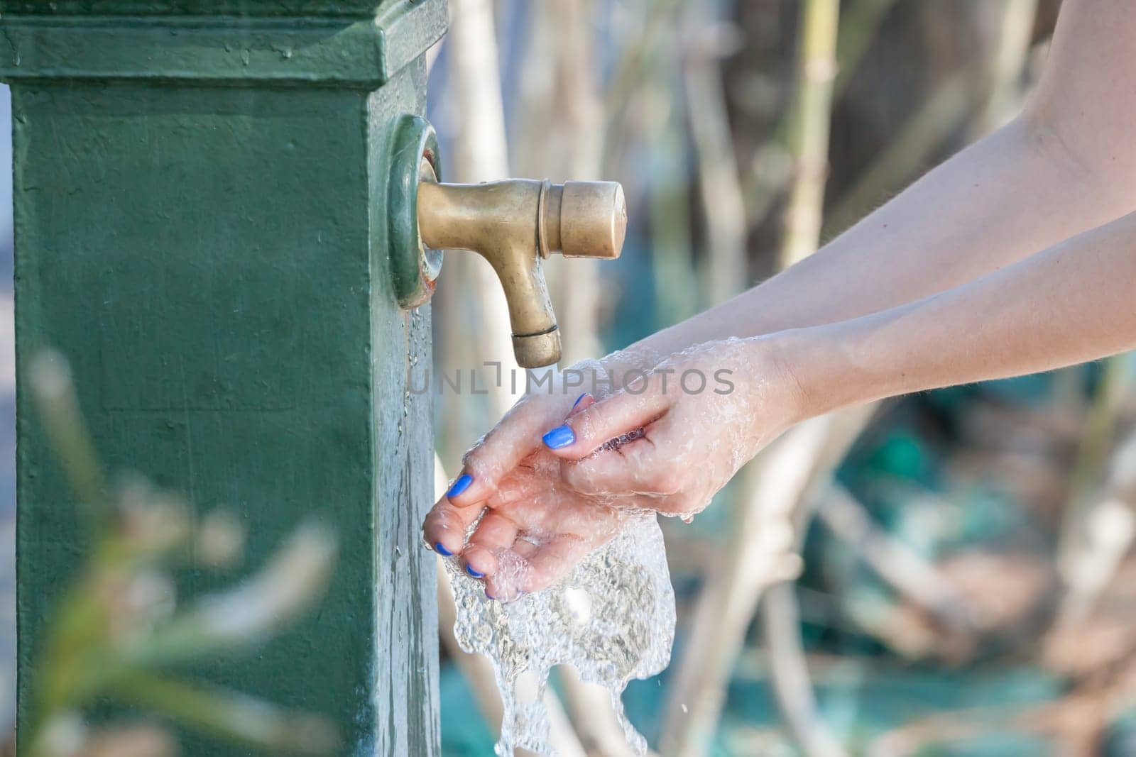 closeup of woman washing hands in city fountain