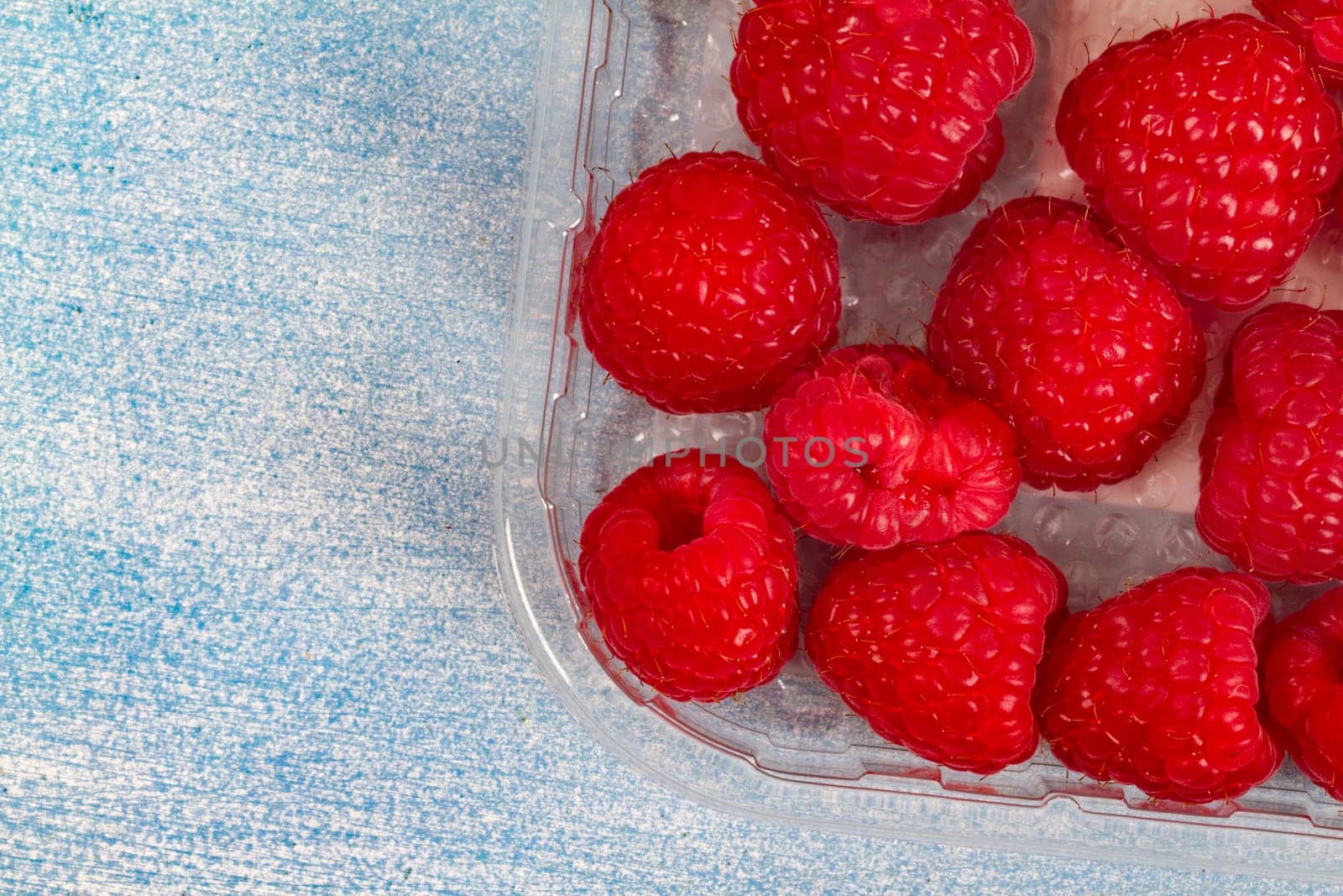 Fresh raspberries on a light blue background