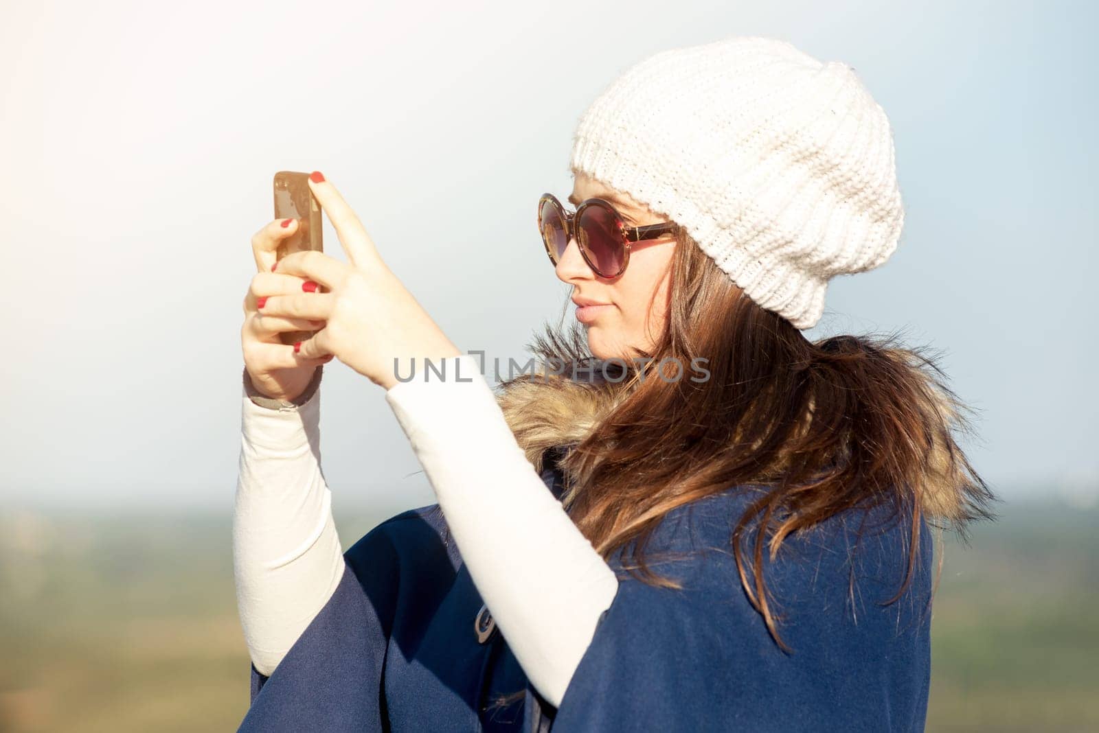 Beautiful happy young girl posing outdoors with phone