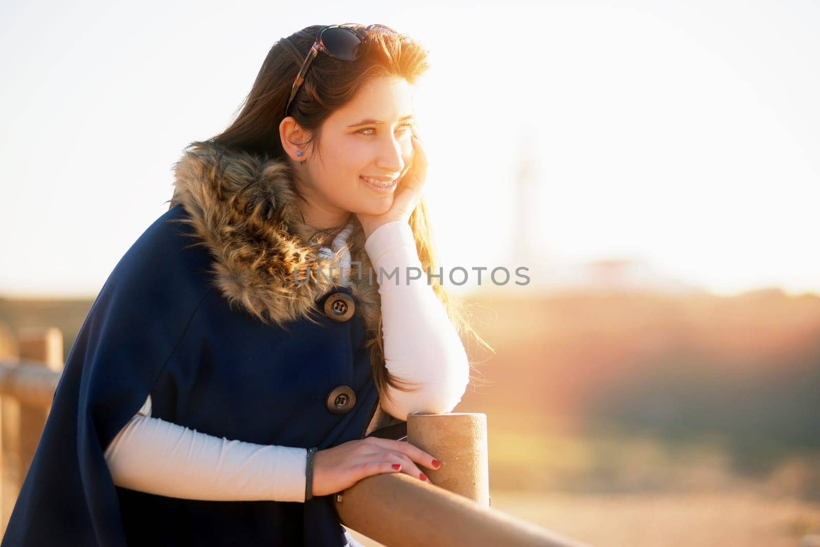 Beautiful happy young girl posing outdoors at sunset near a lighthouse
