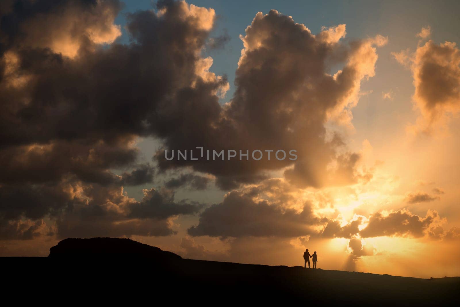 couple holding hands against a beautiful sunset sky