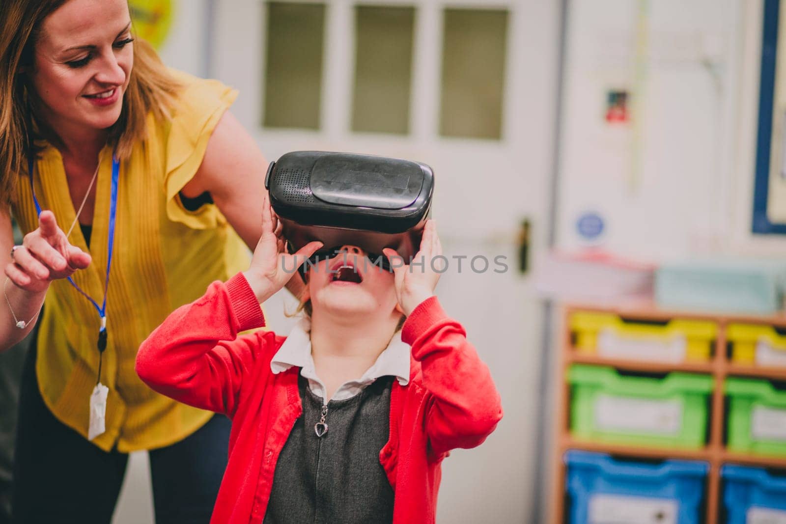 Teacher is helping one of her primary school students use a virtual realtiy headset in the classroom.
