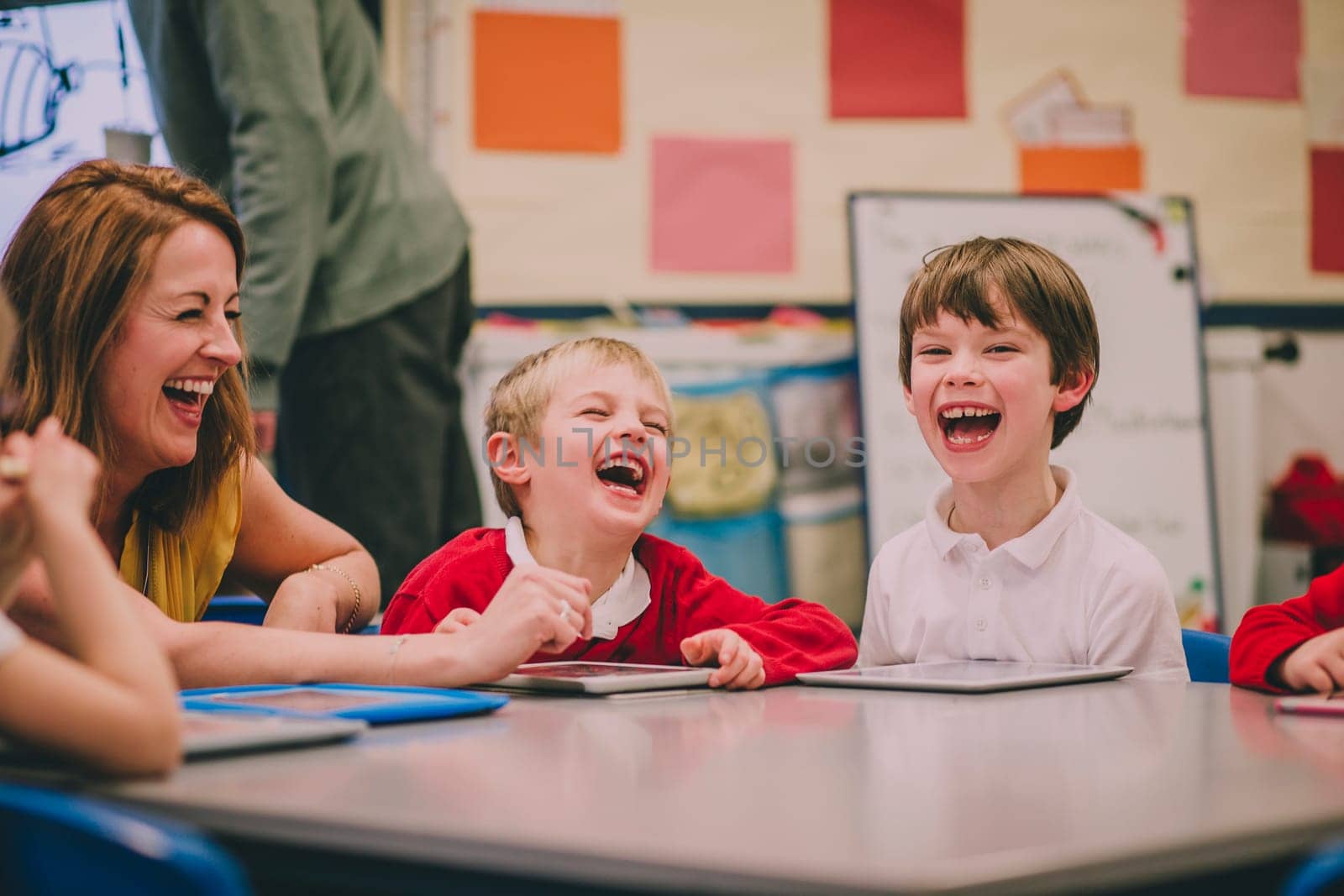 Students are laughing and enjoying themselves during a digital tablet lesson at school.
