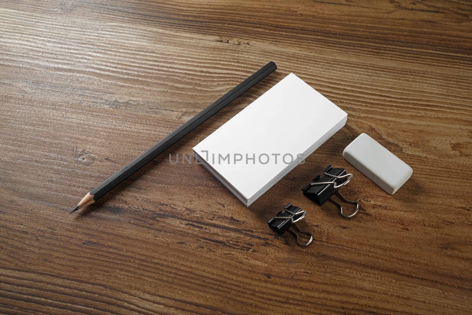 Photo of blank business cards, pencil and eraser on wooden table background. Blank stationery. Mock up for your design. Responsive design template.