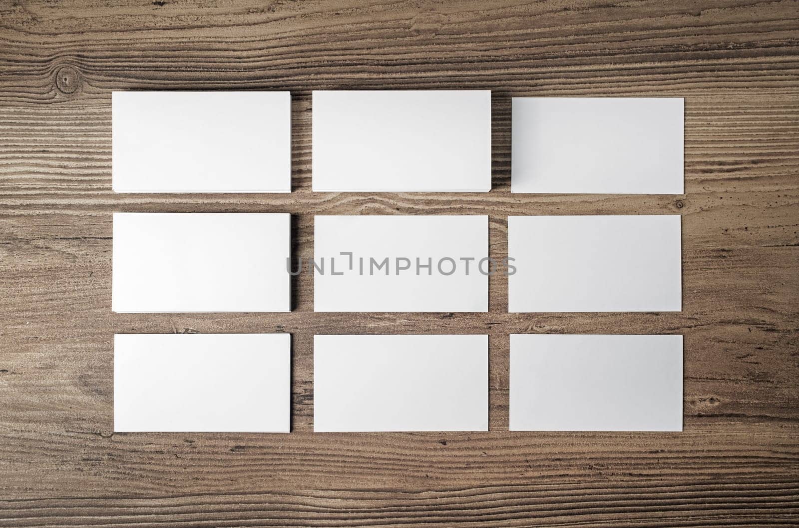 Many blank business cards on wood table background. Blank paperwork template for placing your design. Mockup for ID. Top view.