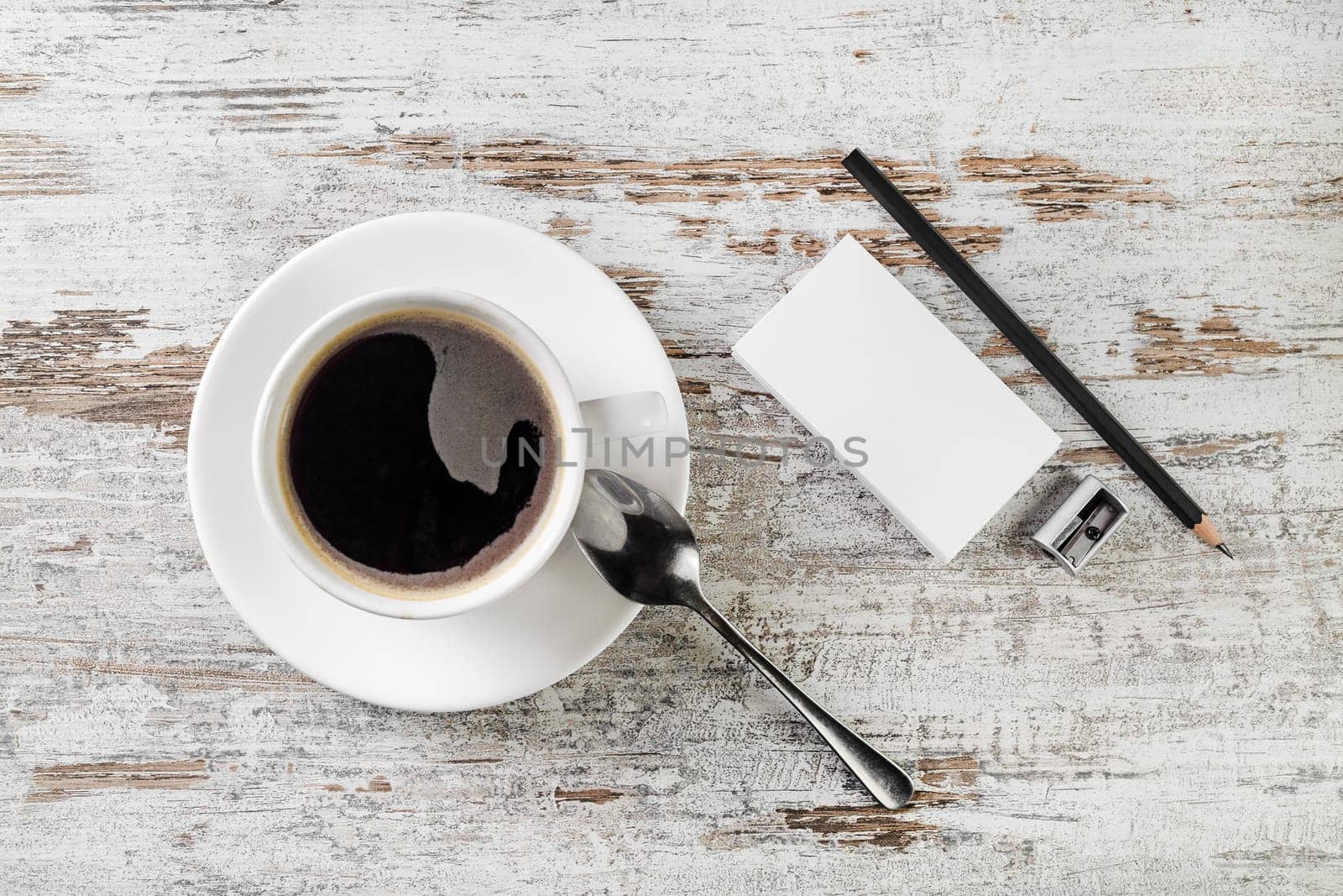 Still life with coffee. Coffee cup, bank business cards, spoon, pencil and sharpener on wooden table background. Top view.