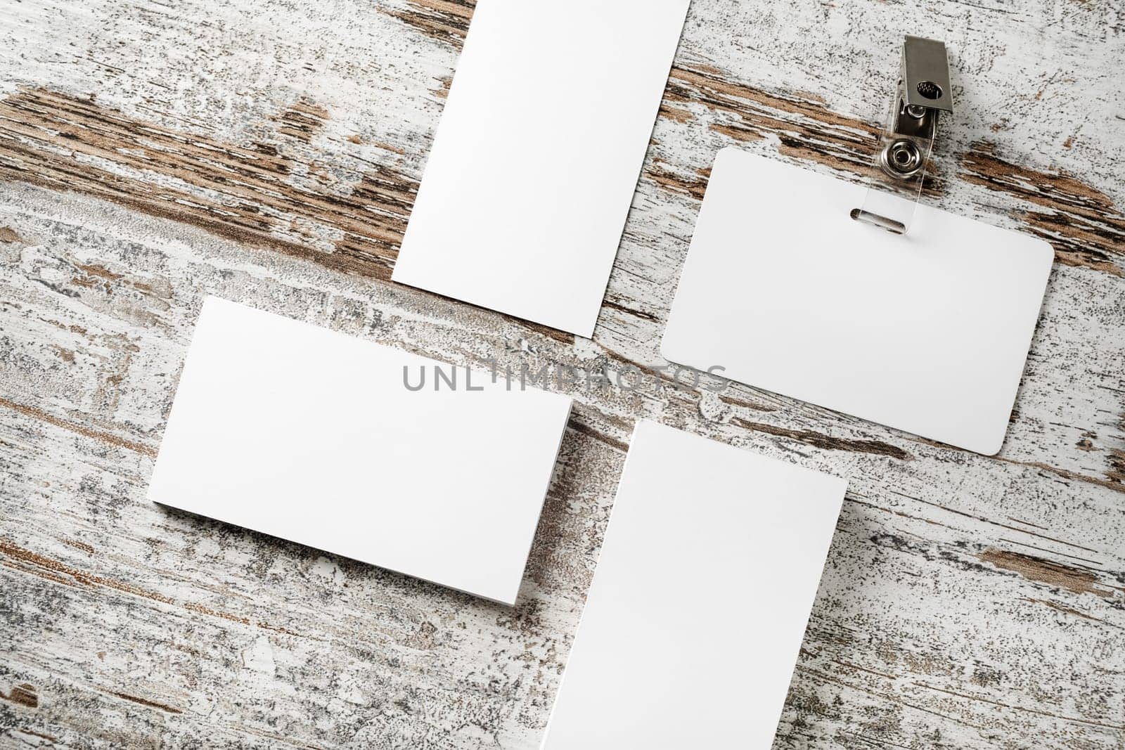 Photo of blank business cards and badge on vintage wooden table background. Blank template for placing your design.