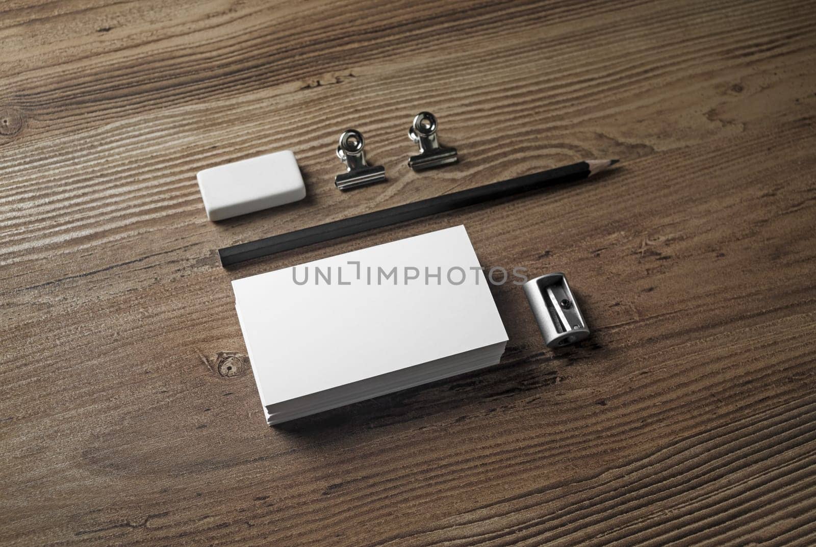 Blank stationery and corporate identity template. Photo of business cards, pencil, eraser and sharpener on wooden background.