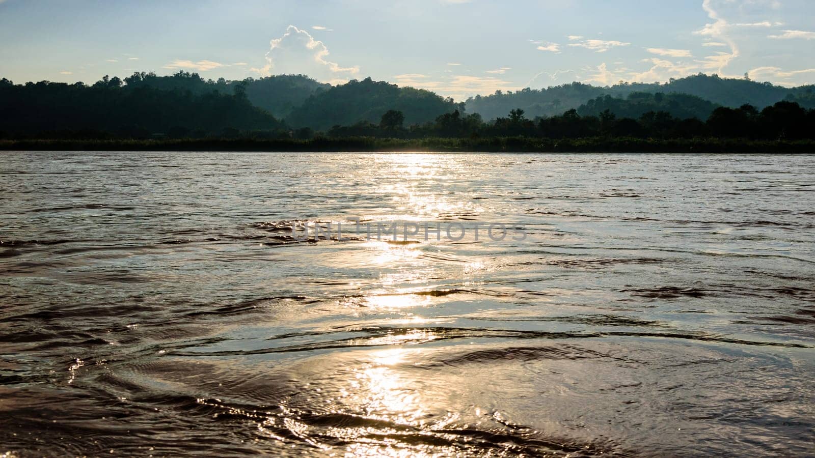 Beautiful natural landscape surface water of the Mekong River reflects golden sunlight during sunset in Thailand, 16:9 wide screen