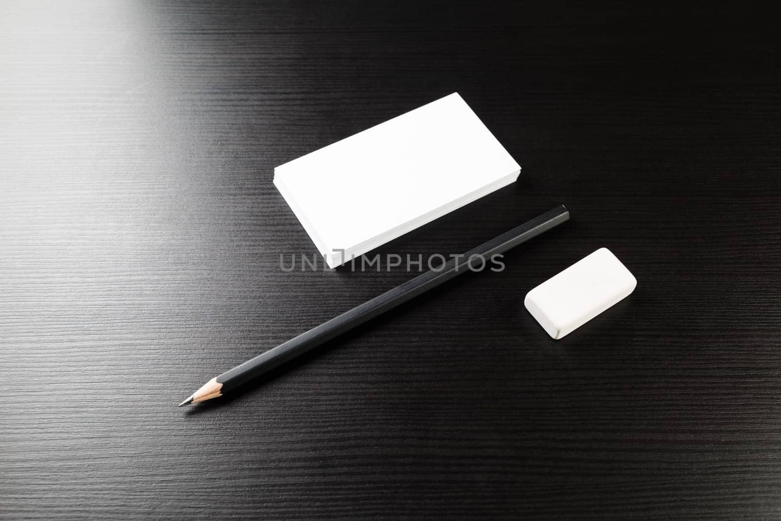 Bank business cards, pencil and eraser on black wood table background. Blank stationery template. For design presentations and portfolios. Top view.