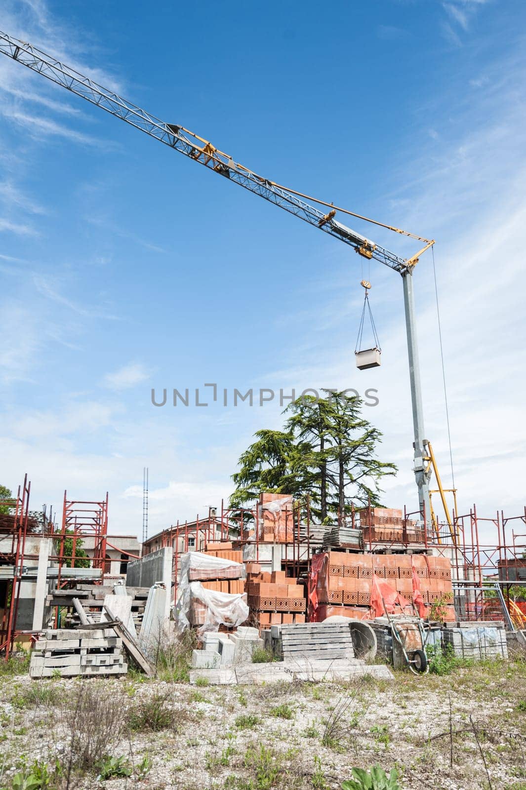 Small construction site with houses under construction. Construction cranes, scaffolding, bricks and other building materials.