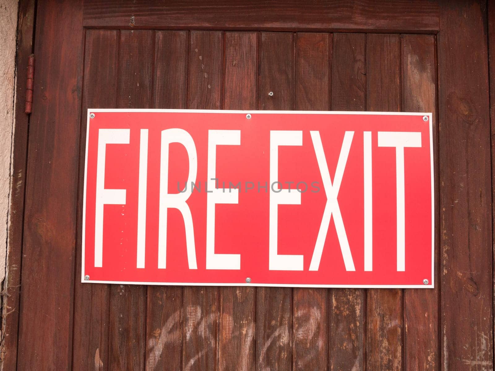 a big red and white sign outside on a fence saying fire exit
