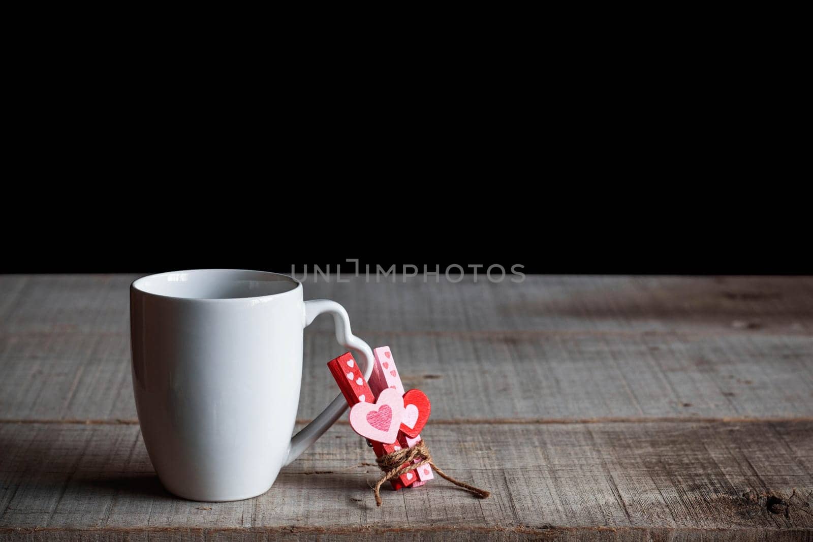 White coffee cup with heart on old wooden table.
