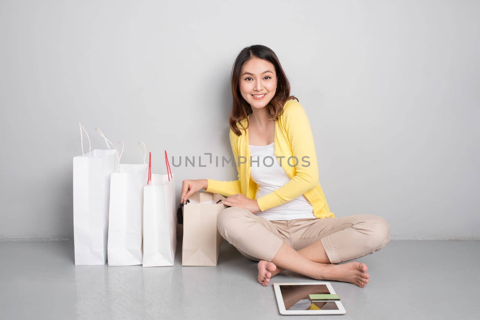 Young asian woman shopping online at home sitting besides row of shopping bags