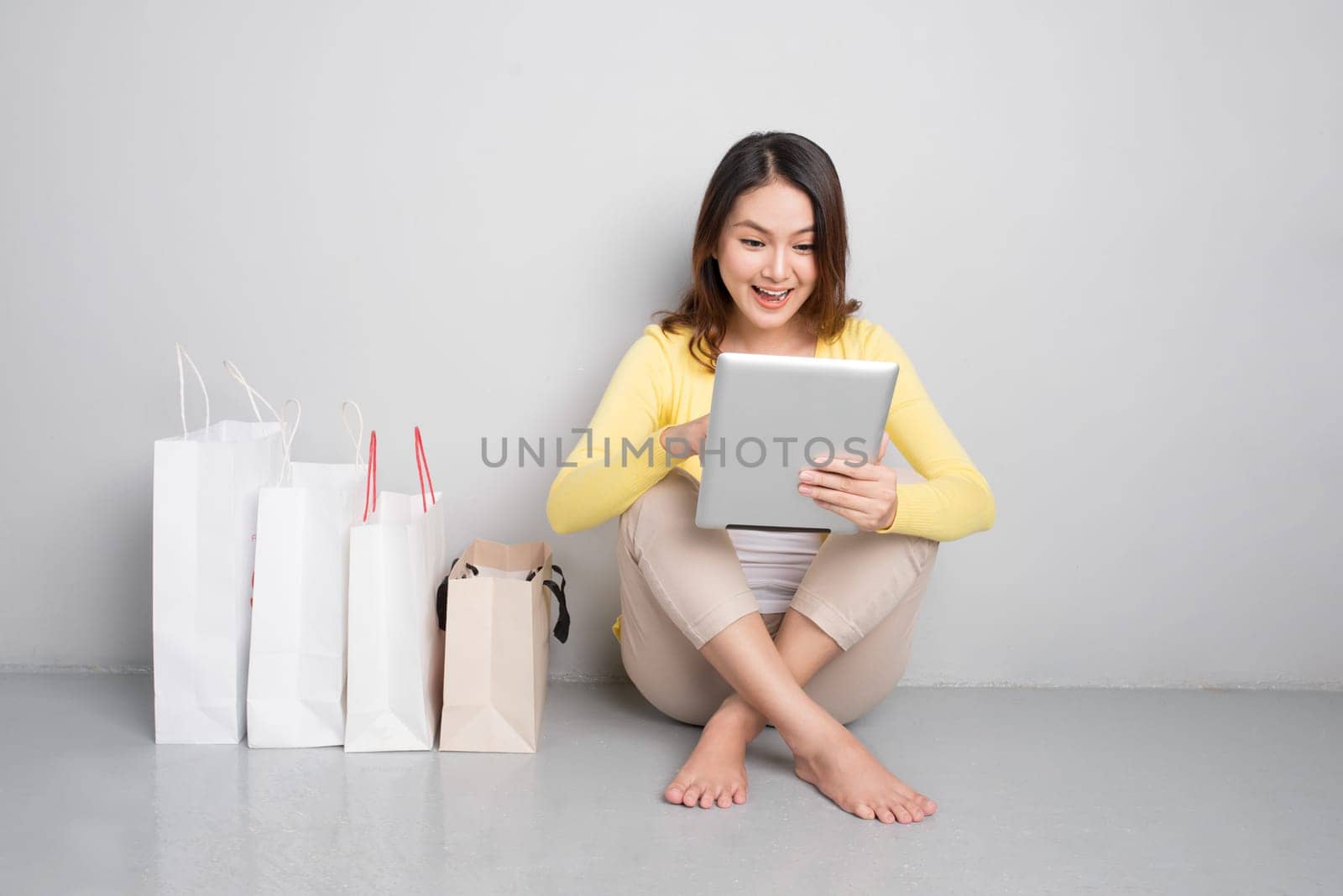 Young asian woman shopping online at home sitting besides row of shopping bags