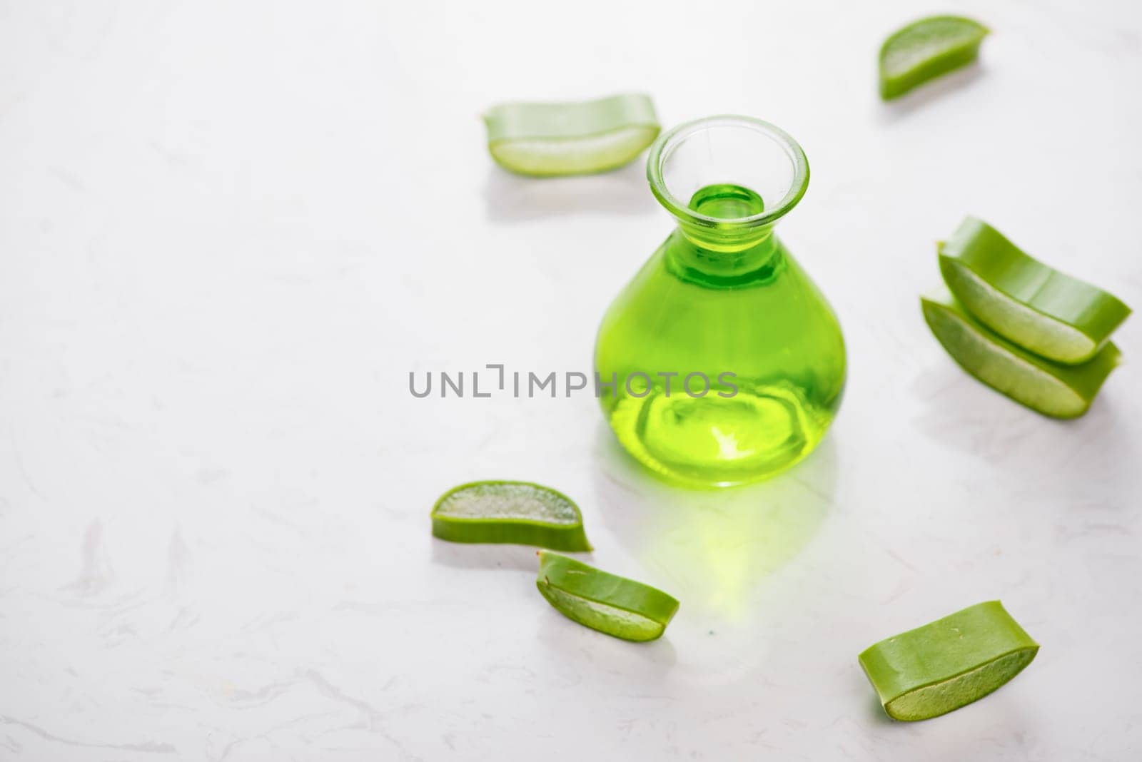 Aloe vera essential oil and aloe leaves on a white background.