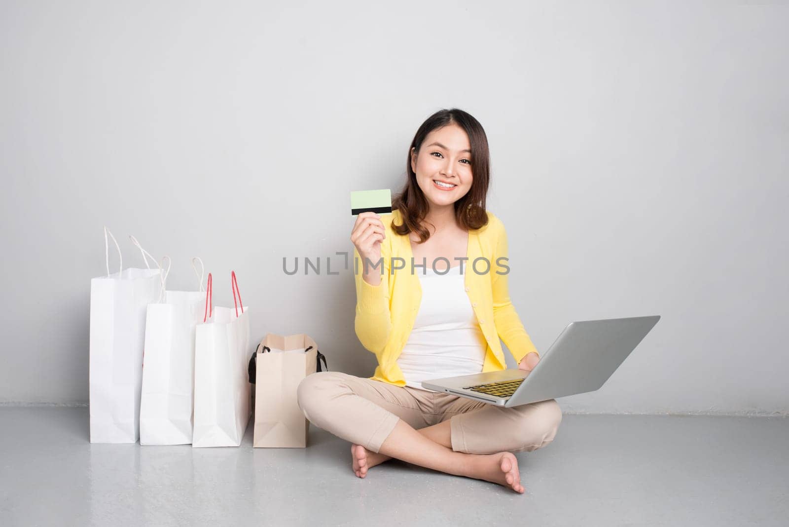 Young asian woman shopping online at home sitting besides row of shopping bags