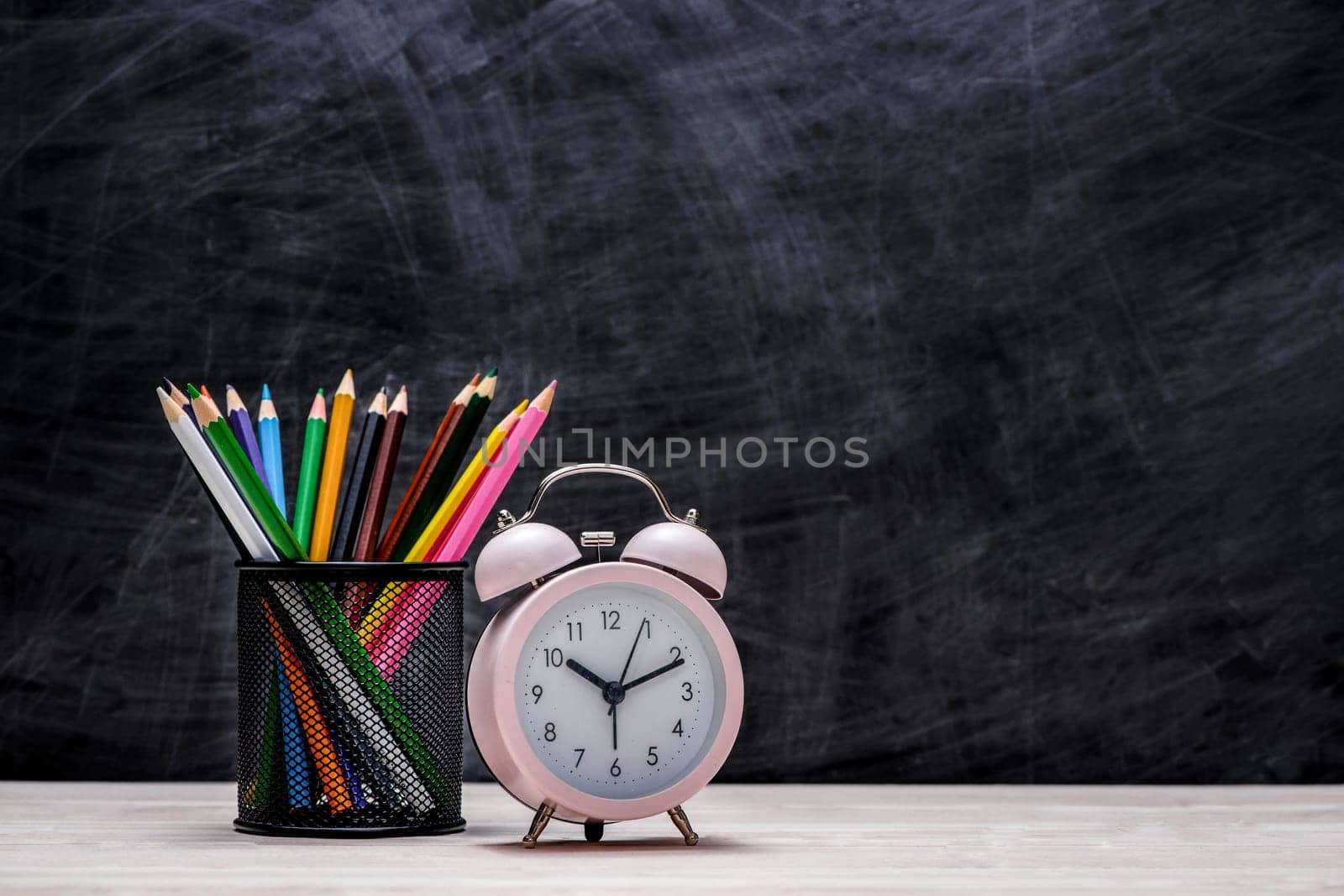 School and office supplies and apple in front of blackboard.