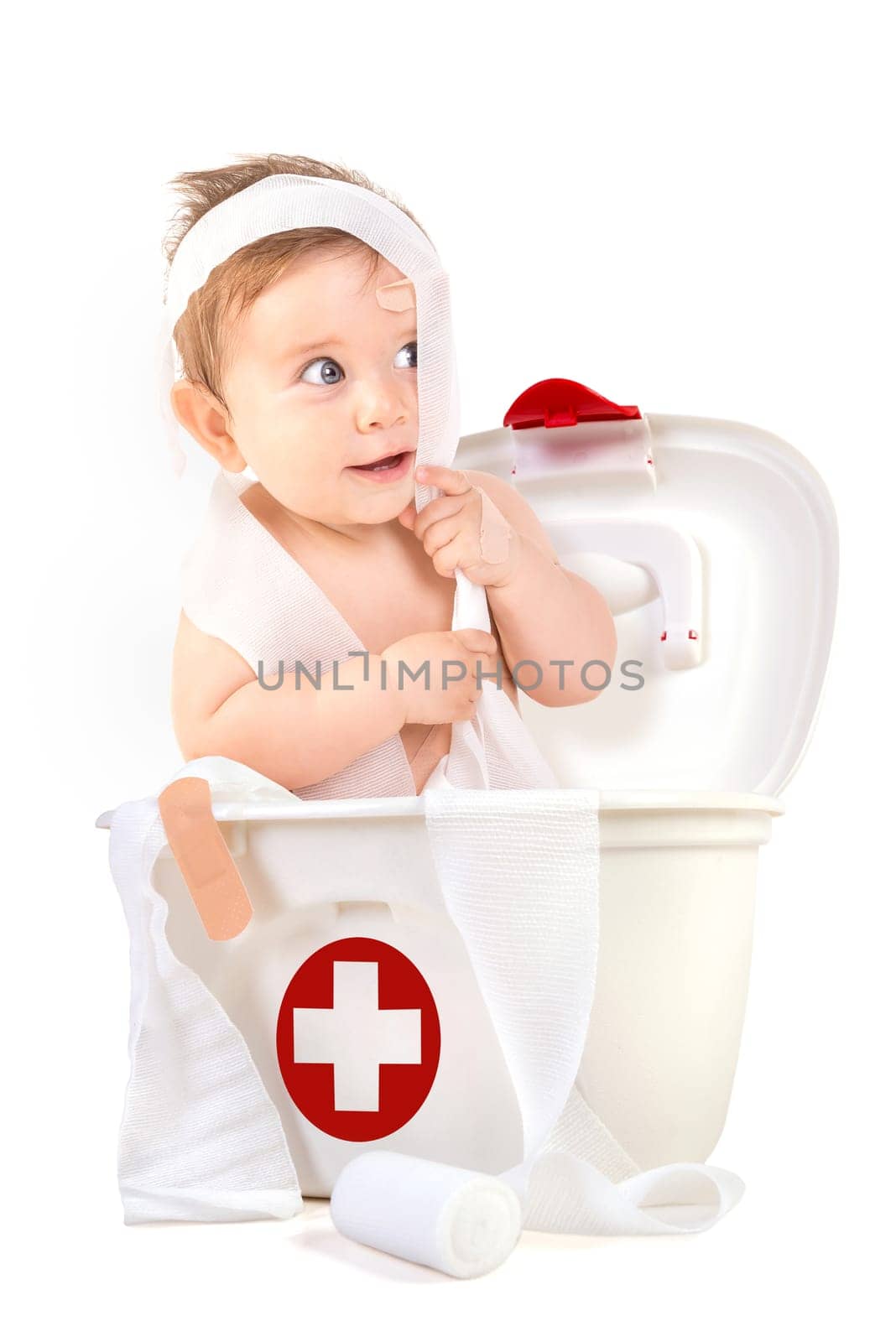 Cute baby boy playing with bandages in a first aid kit box.