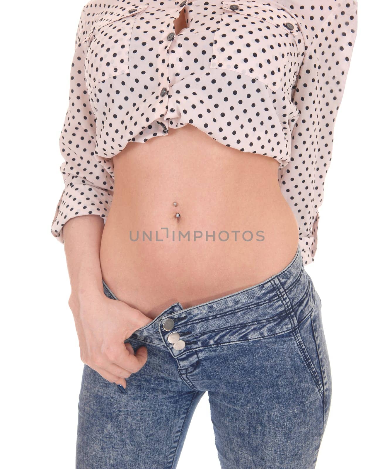 A closeup image of a young woman's flat stomach, in jeans and a.blouse standing isolated for white background..