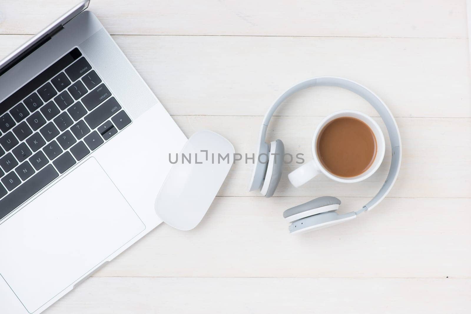 Laptop computer on white table with headphone and coffee cup. View from above