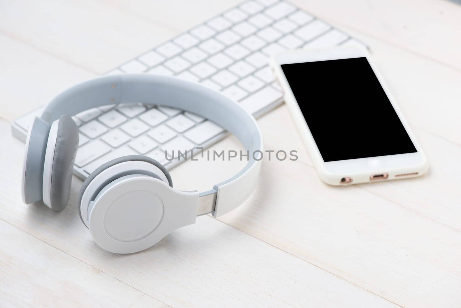 Notepad and computer keyboard on white table with headphone. View from above