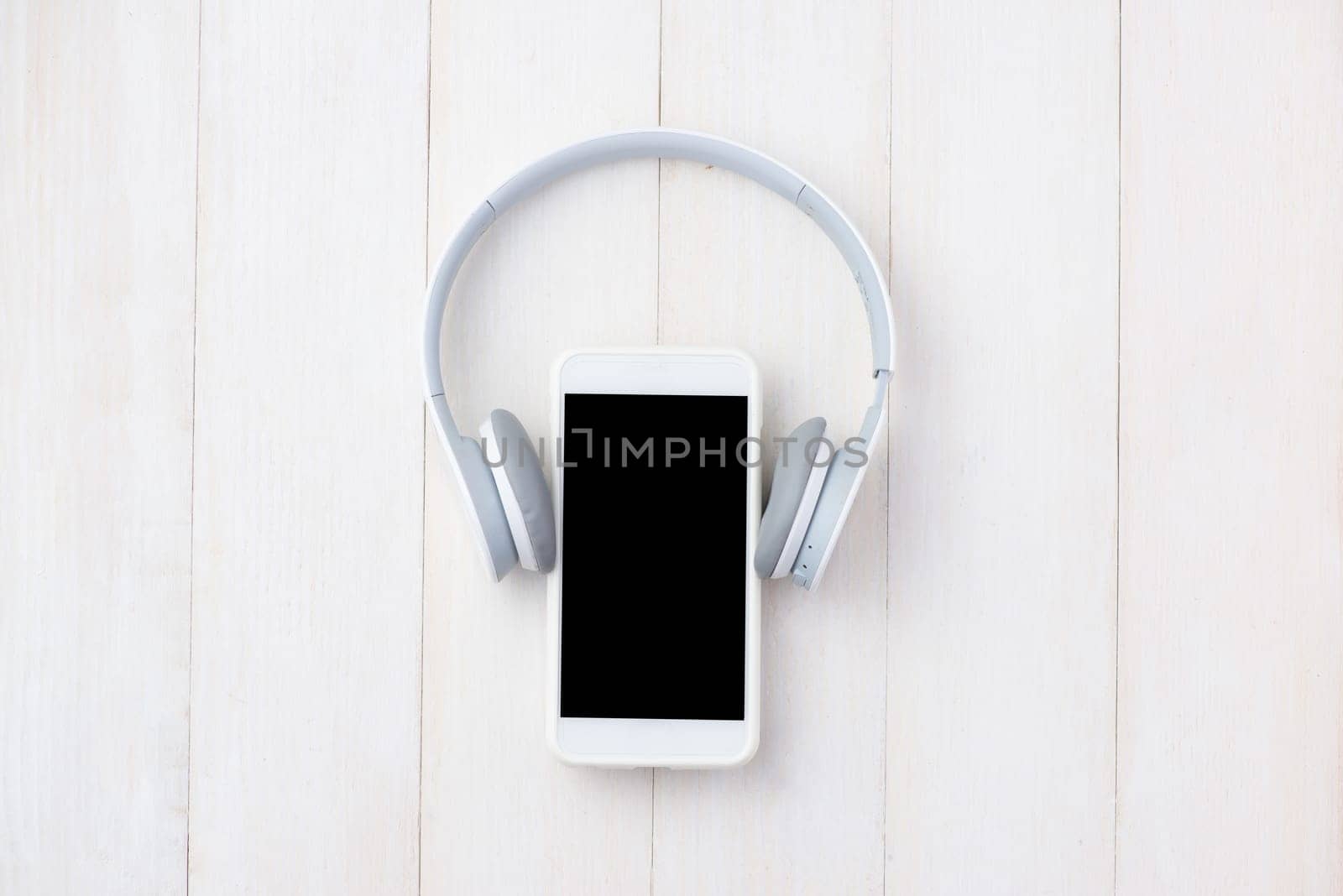 Headphone and mobile phone on white table with headphone. View from above