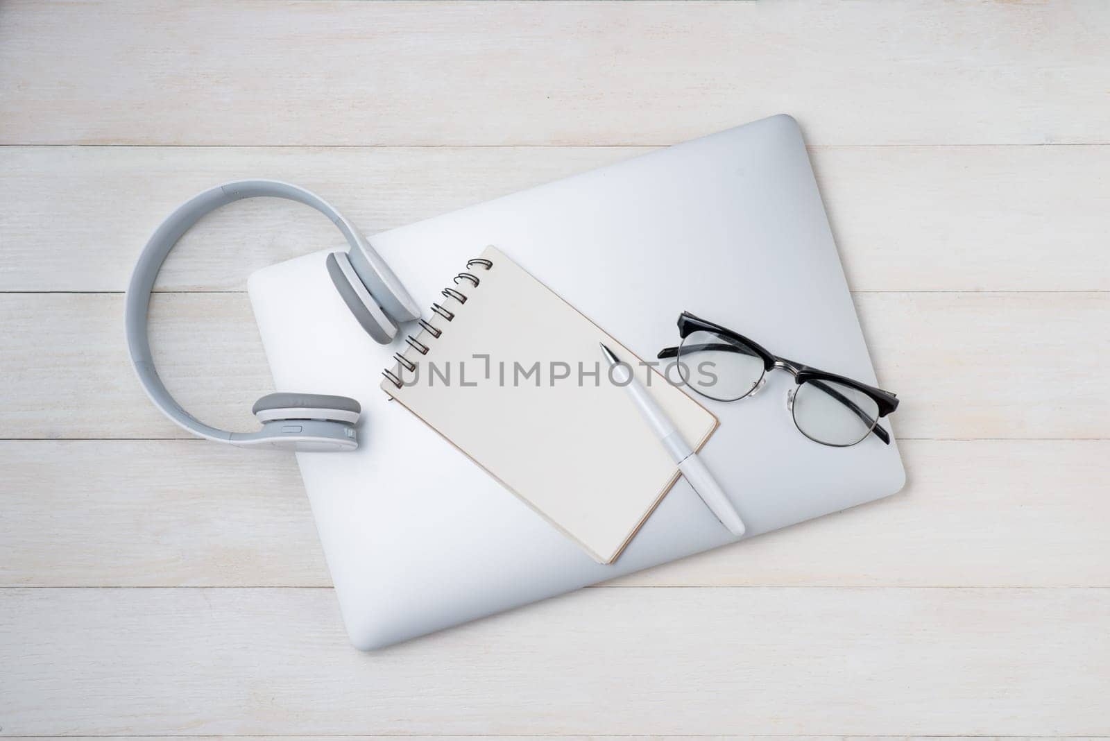 Notepad and computer keyboard on white table with headphone. View from above