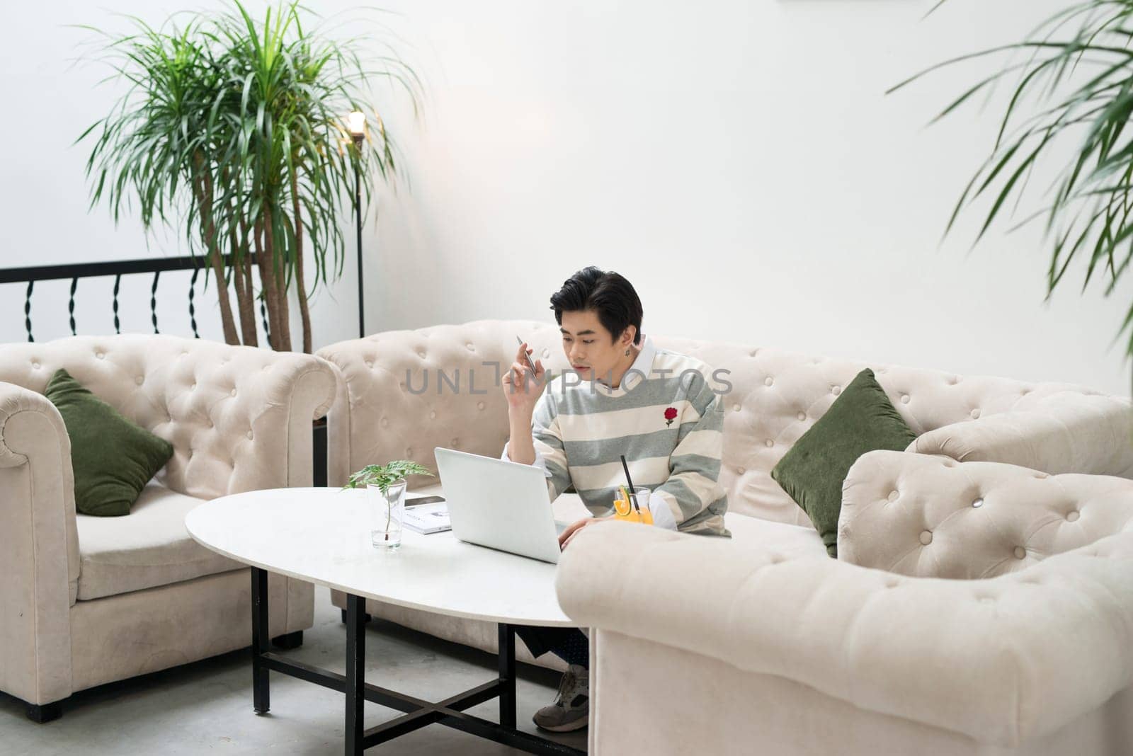 Asian young businessman working on his laptop in a coffee shop