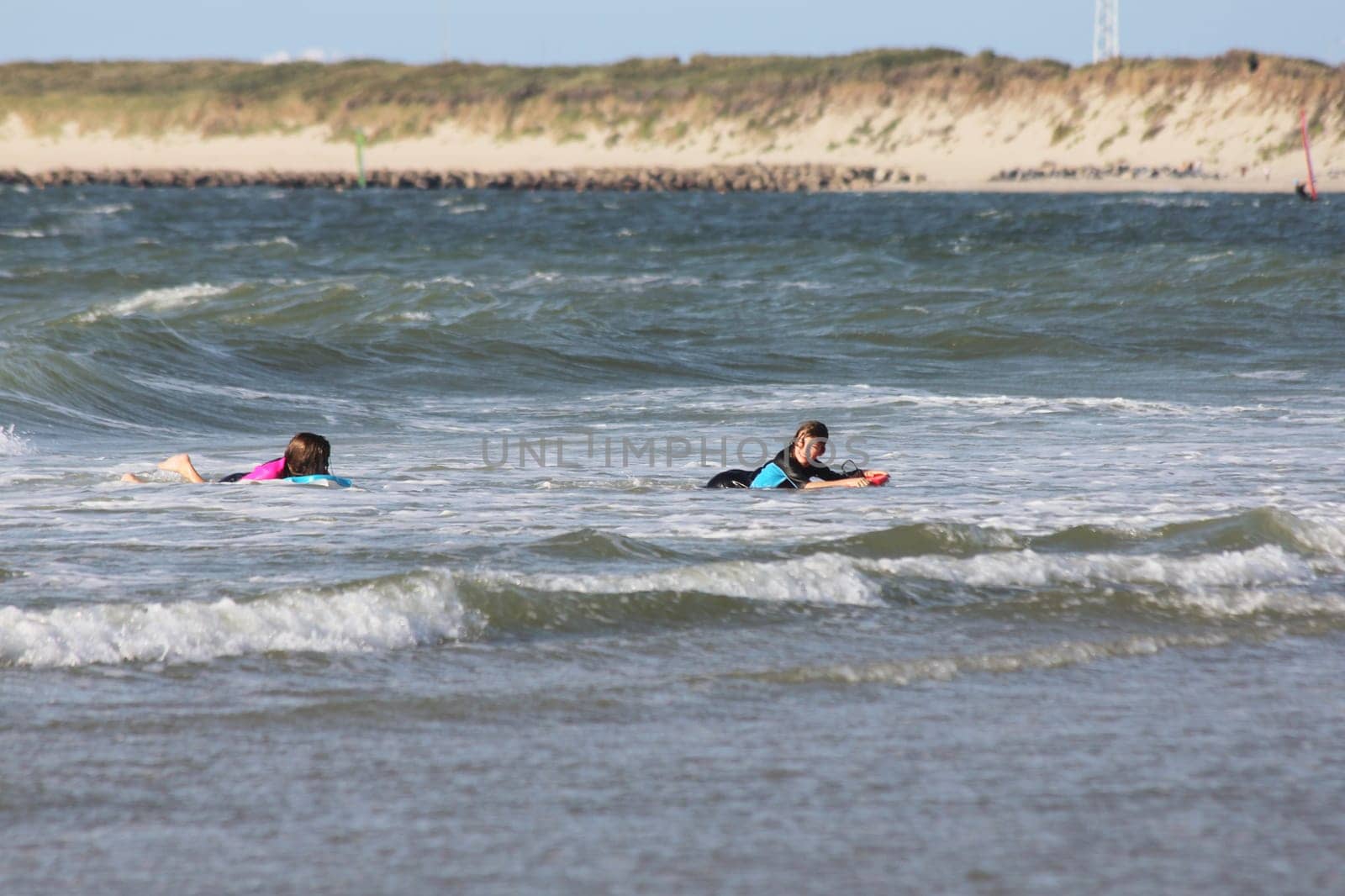 two blonde girls bathing in the sea.