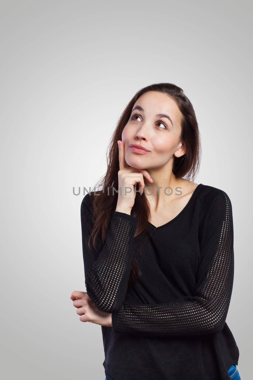 Young woman looking up at copy space, on grey background