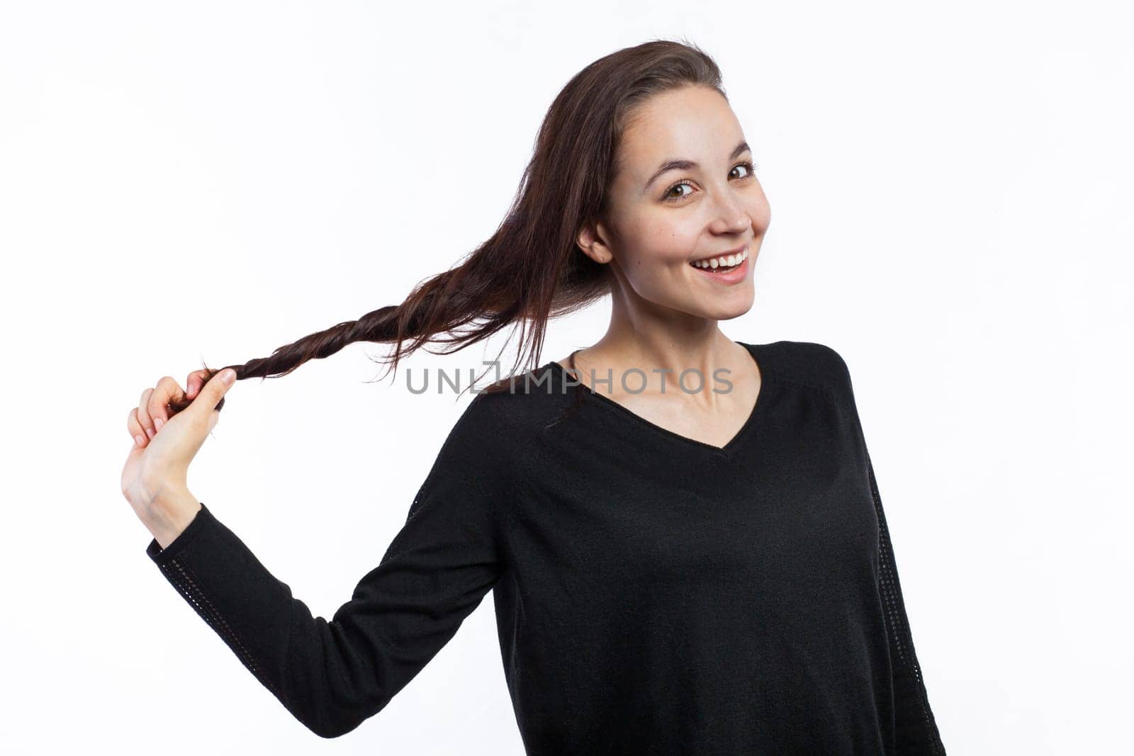 Portrait of a cute young woman pulling her hair, isolated on white