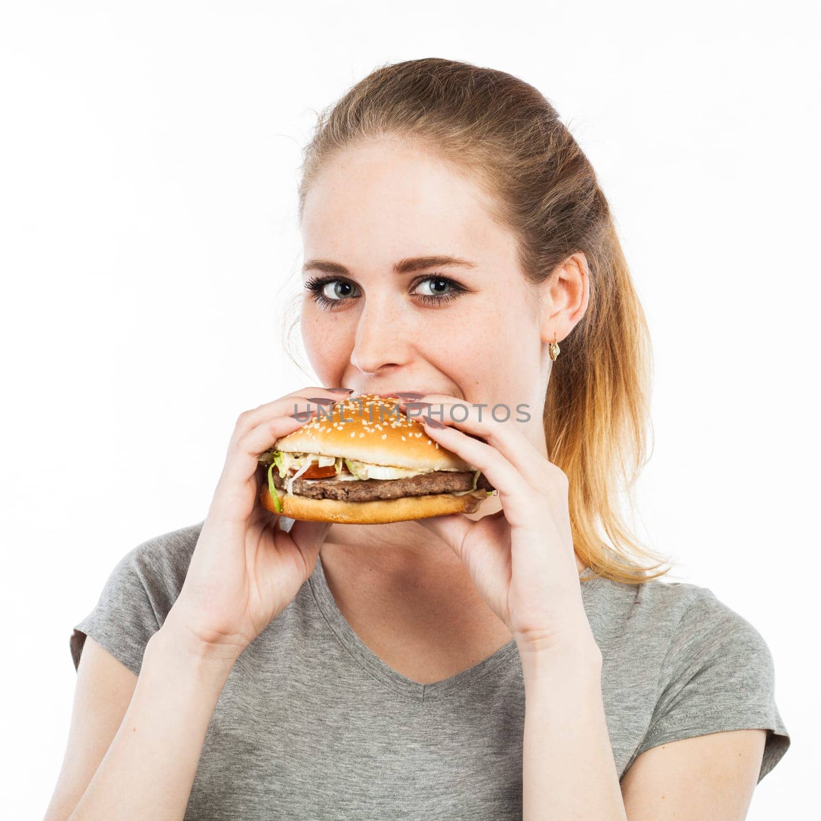 Portrait of a cute young woman eating a burger, isolated on white